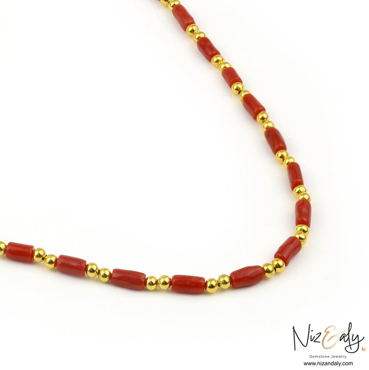 Niz & Aly natural red coral barrel bead necklace with polished gold round spacers on a white background.
