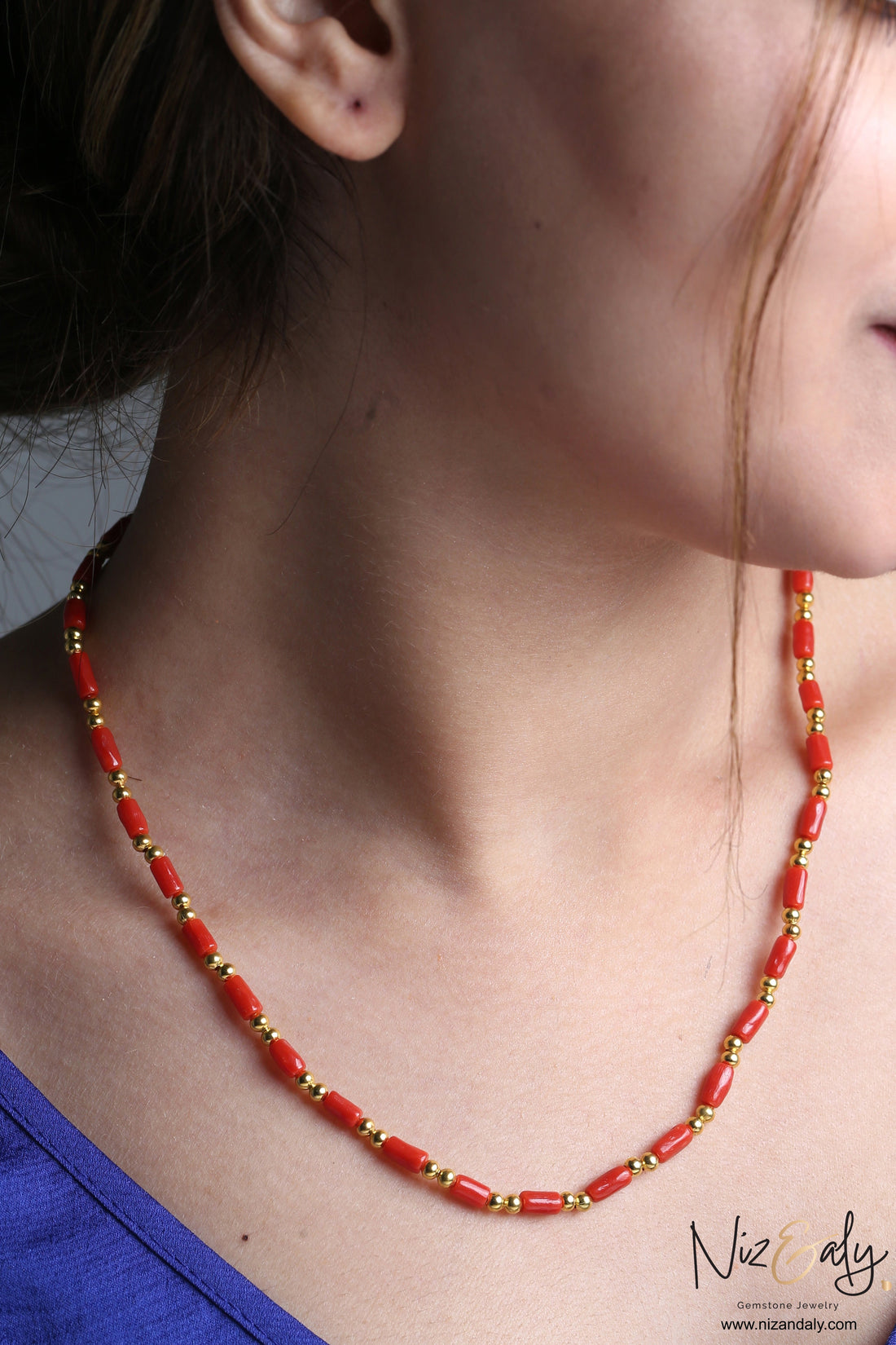 Niz & Aly natural red coral barrel bead necklace with polished gold accents worn on a woman's neck