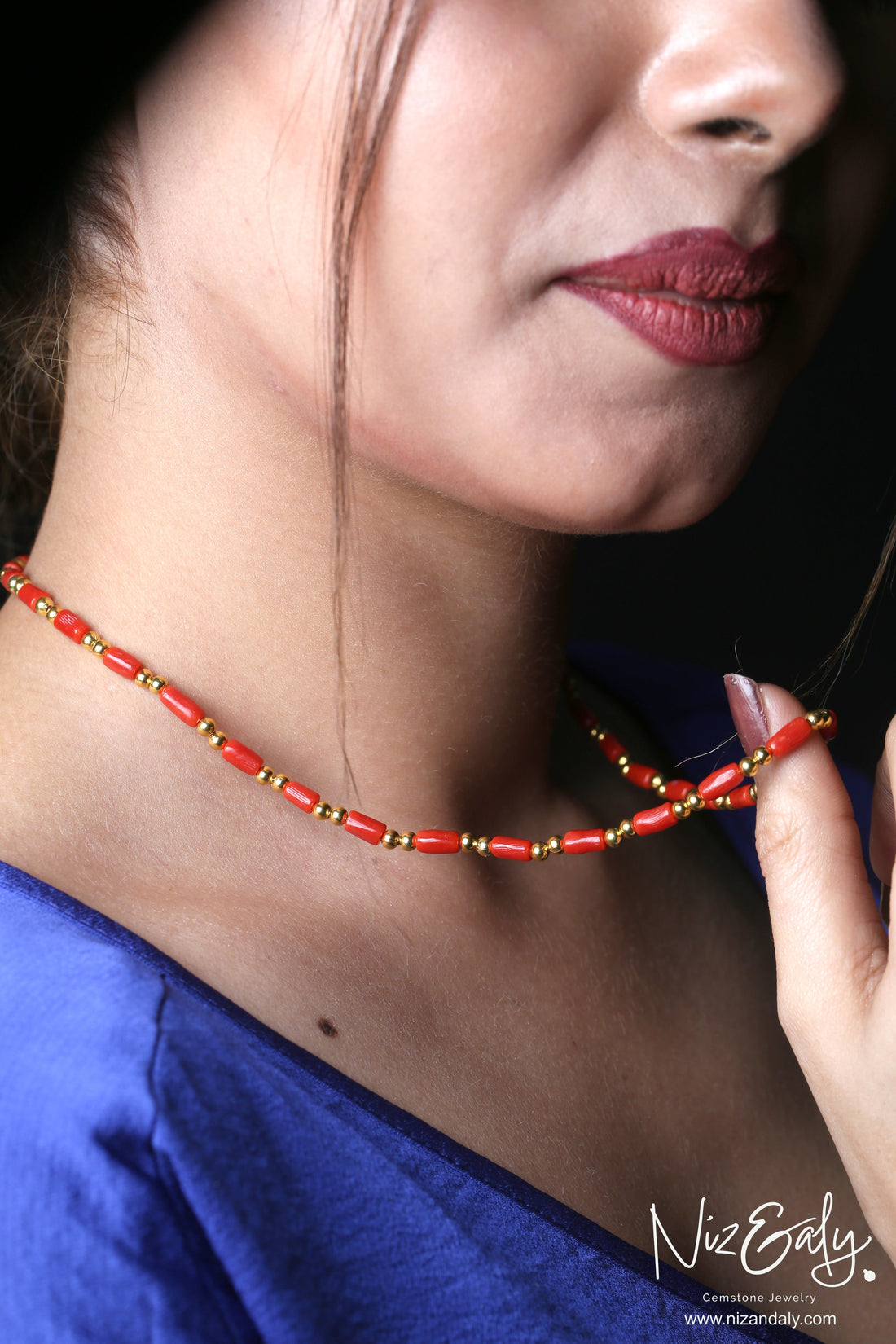 Niz & Aly natural red coral barrel bead necklace with gold accents worn on a woman's neck