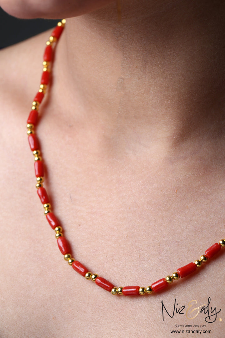 Niz & Aly natural red coral barrel bead necklace with polished gold accents worn on a woman's neck