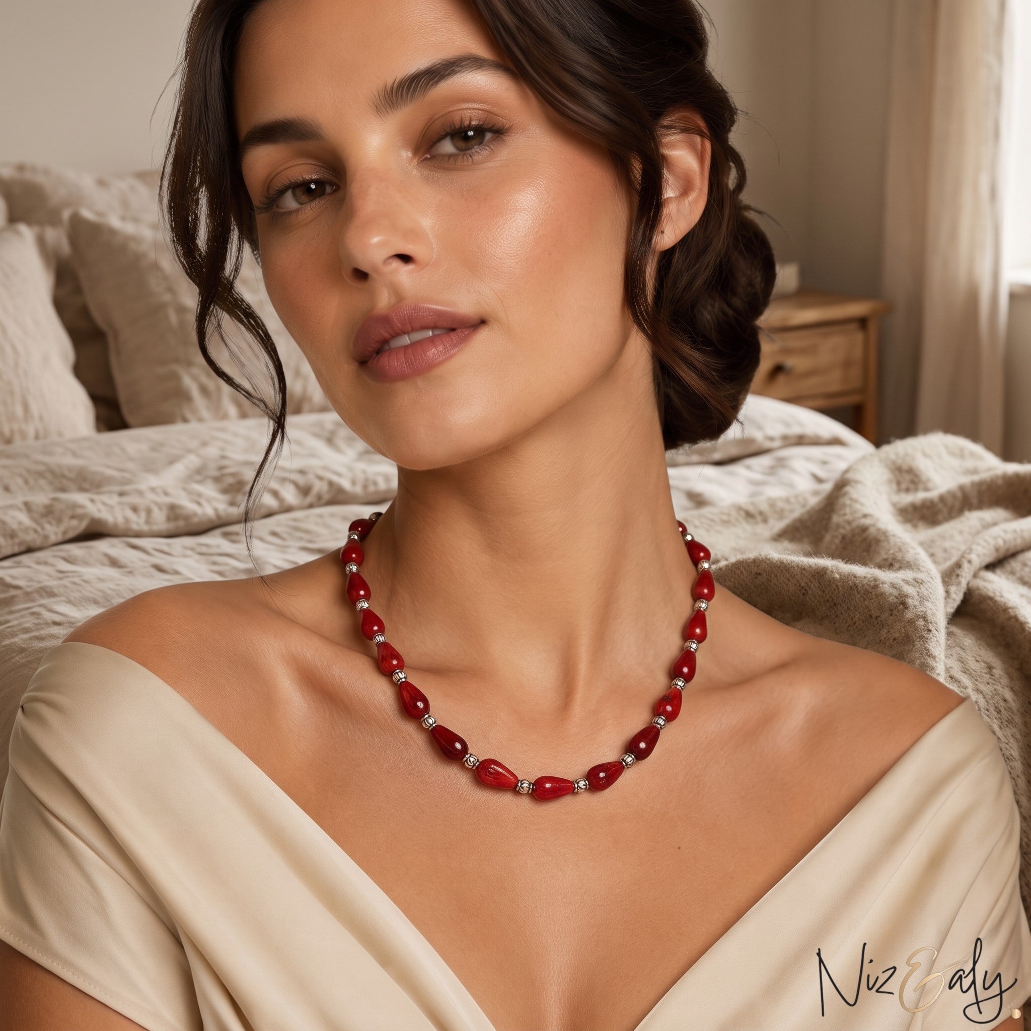 Niz & Aly Rossa Lacrima necklace featuring natural red coral teardrop beads on a woman wearing a beige off-shoulder top.