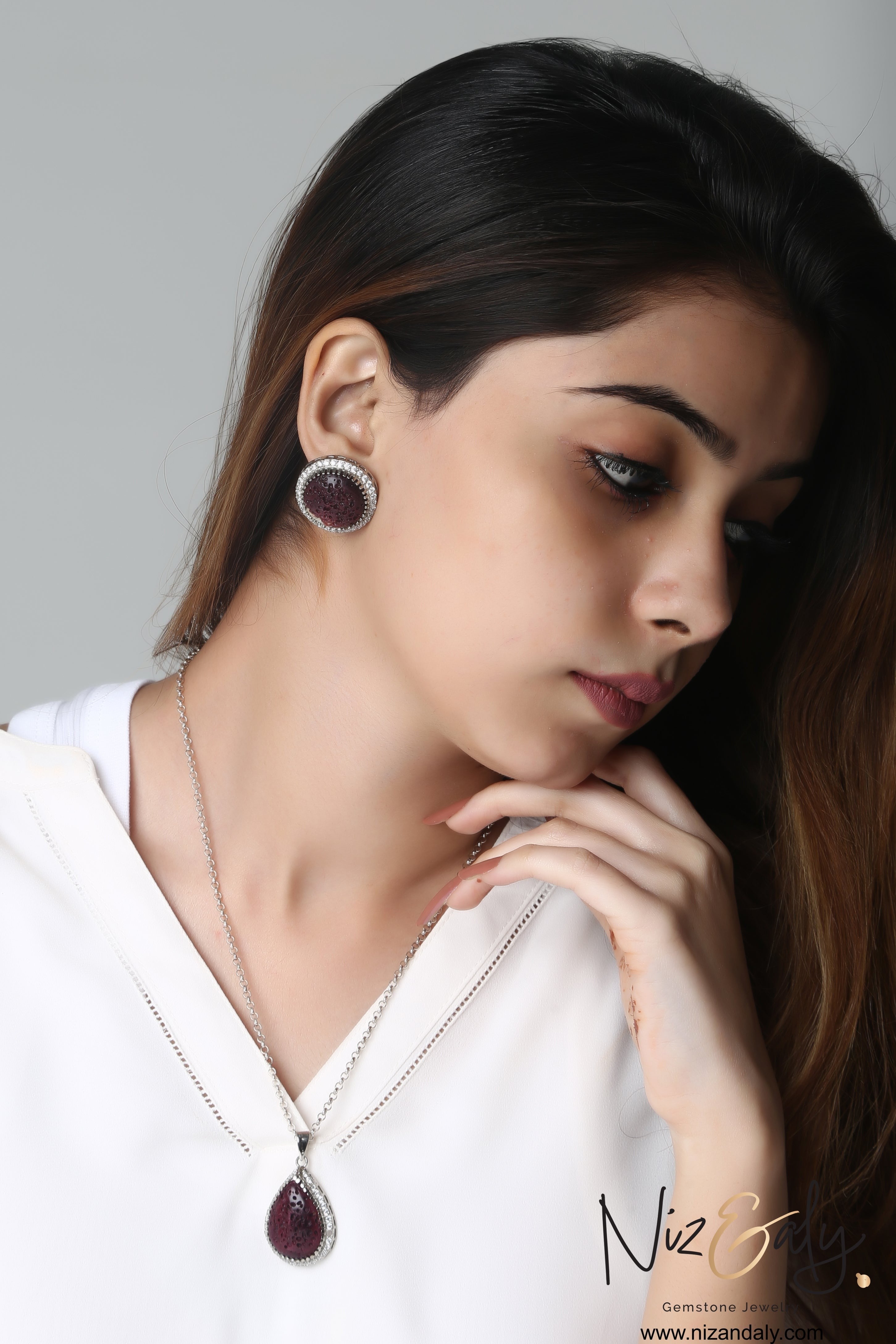 Niz & Aly natural red lava stone pendant and earring set with silver-toned frames worn by a woman