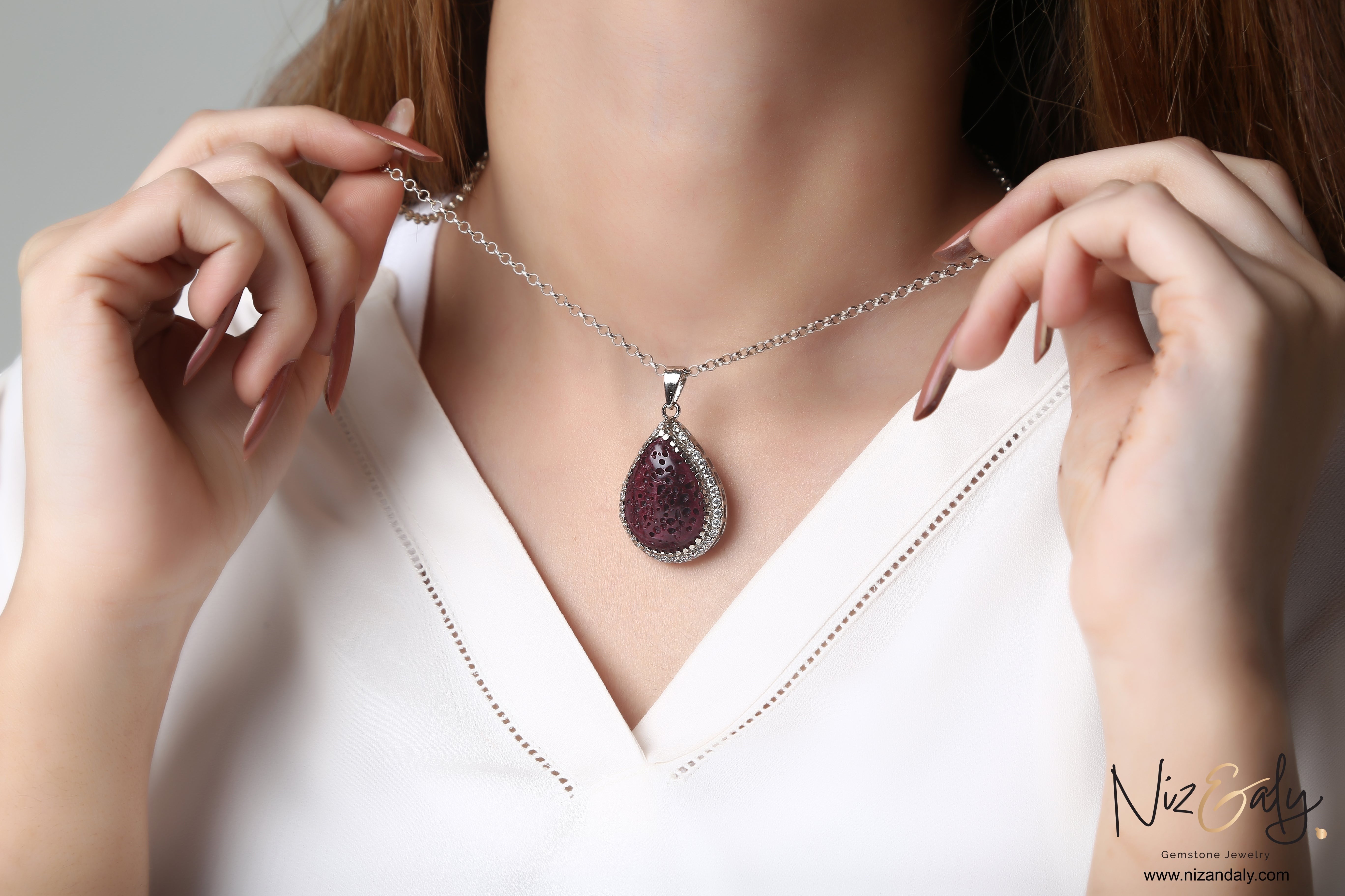 Niz & Aly teardrop red lava stone pendant necklace with silver setting worn on a woman's neck
