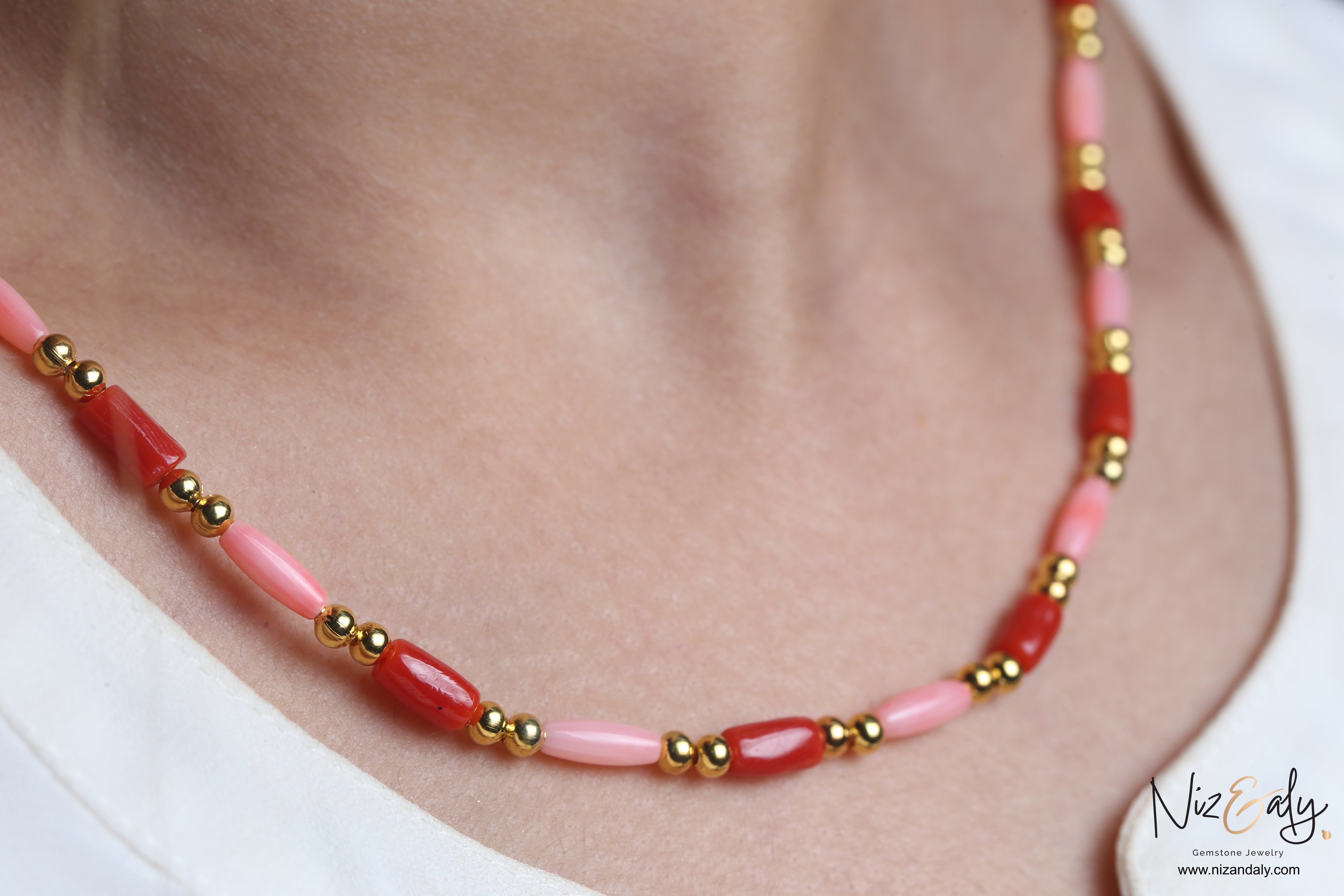 Niz & Aly dainty necklace featuring red and pink rice-shaped natural coral beads accented with polished gold spheres.
