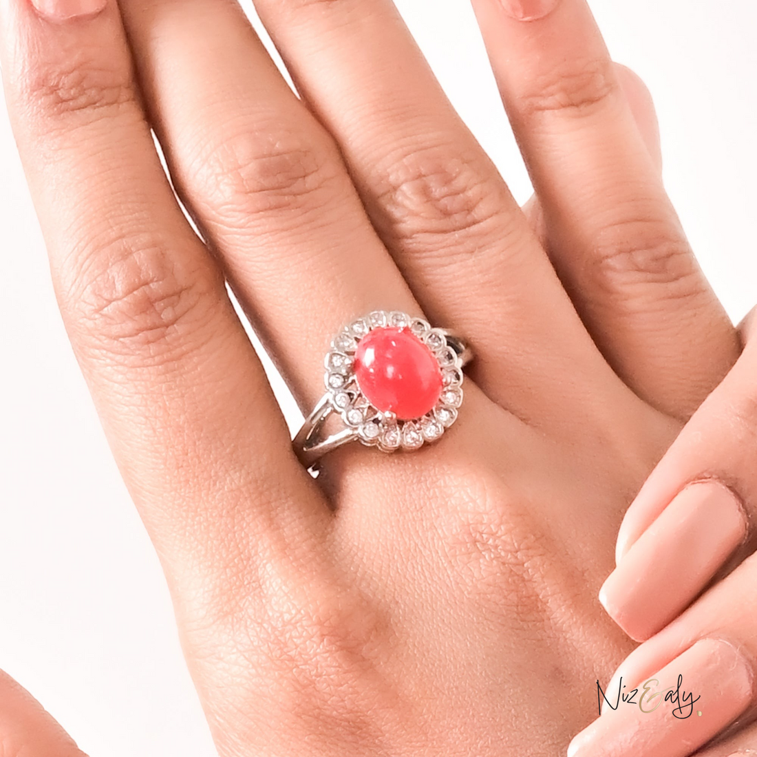 Niz & Aly red cabochon rubelite tourmaline ring surrounded by a halo of sparkling diamonds on a woman's finger