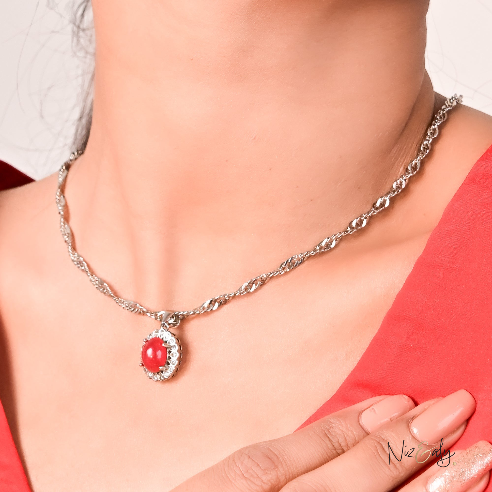 Niz & Aly red cabochon rubellite tourmaline locket pendant on a silver twisted chain worn around a woman's neck