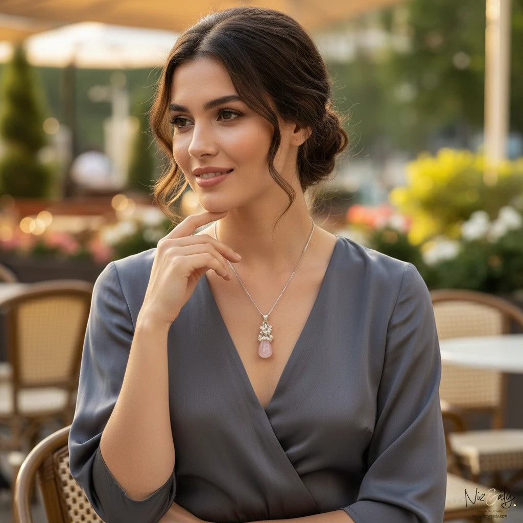 Niz & Aly rose quartz and pearl teardrop pendant necklace worn by a woman in a grey dress at an outdoor cafe