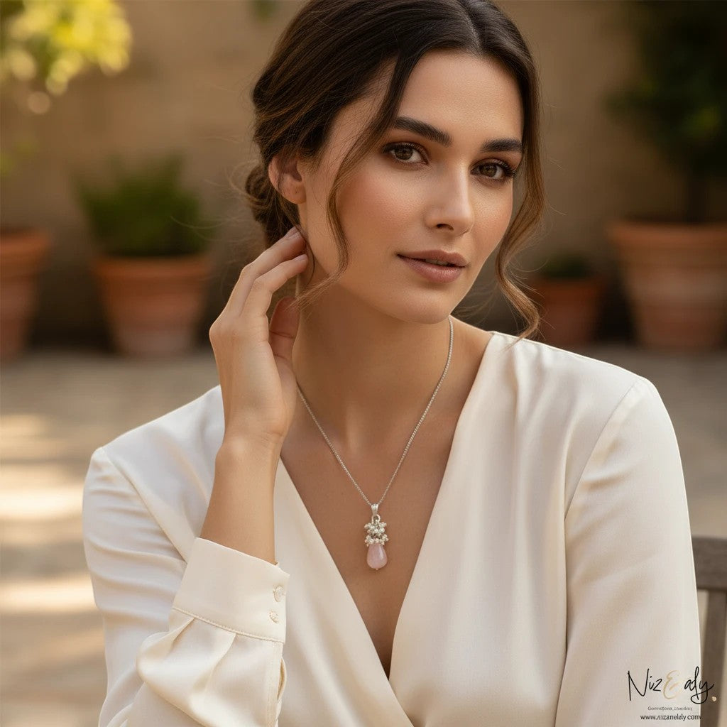 Niz & Aly dainty rose quartz and freshwater pearl teardrop pendant necklace worn by a woman in a white blouse.