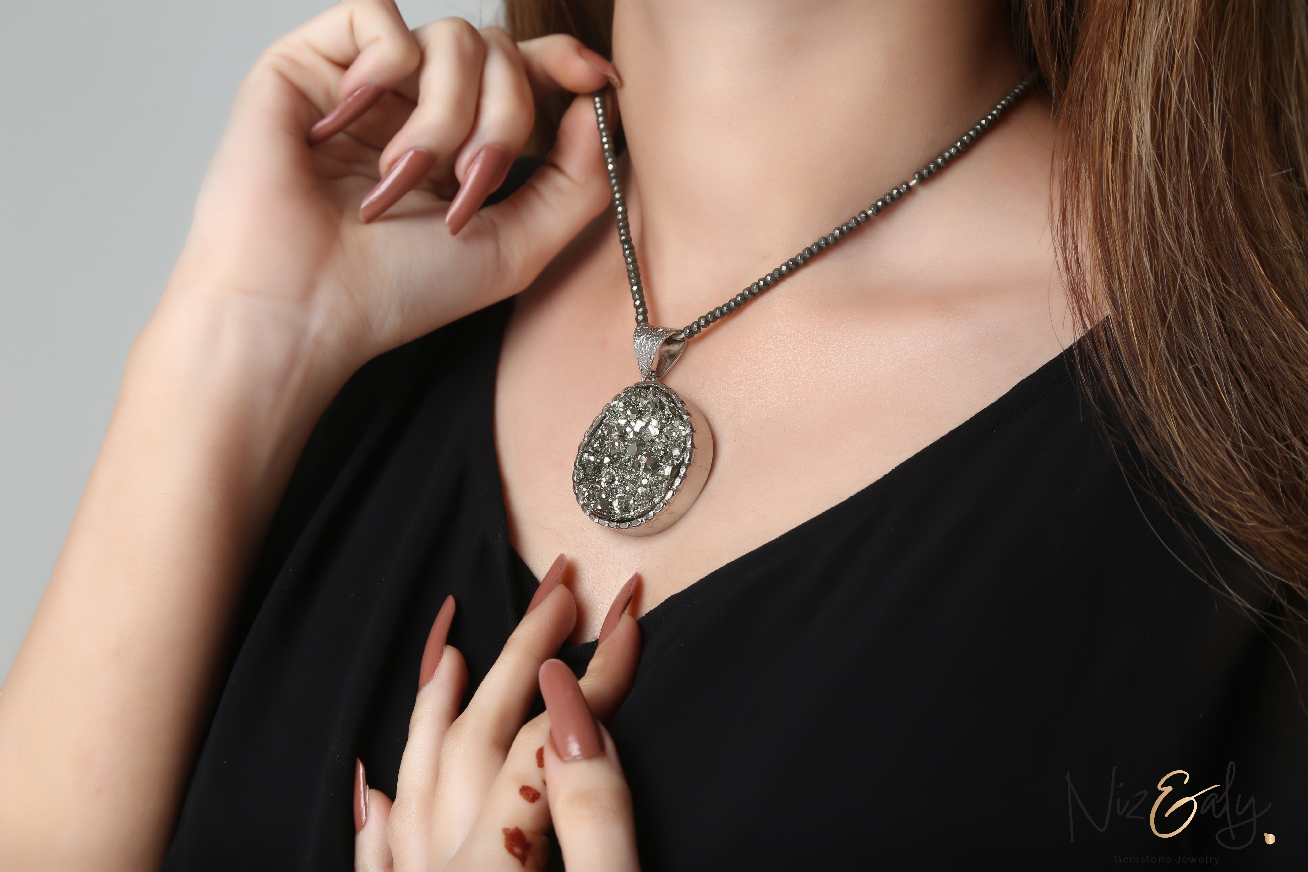 Niz & Aly round pyrite pendant necklace with faceted beads worn by a woman in a black top