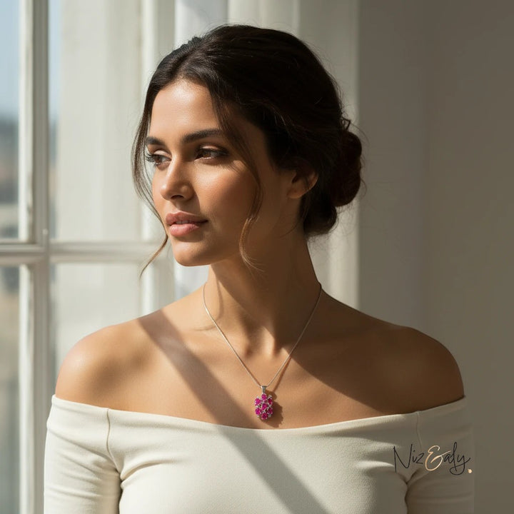 Niz & Aly Lucky 7 pendant featuring seven vibrant red rubies in a cluster design worn by a woman in a white top.