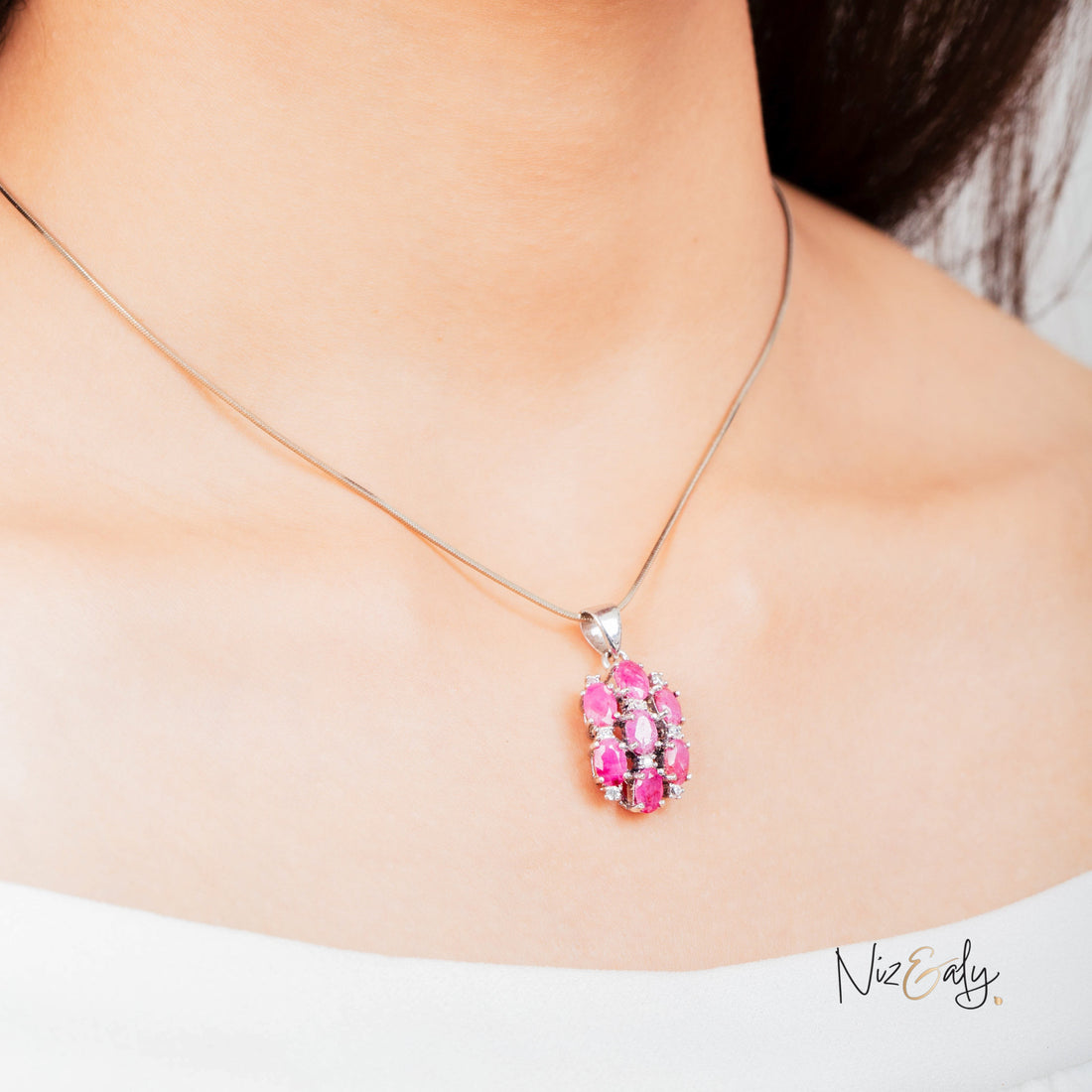 Niz & Aly cluster pendant featuring seven high-quality oval rubies on a delicate silver chain worn by a woman.