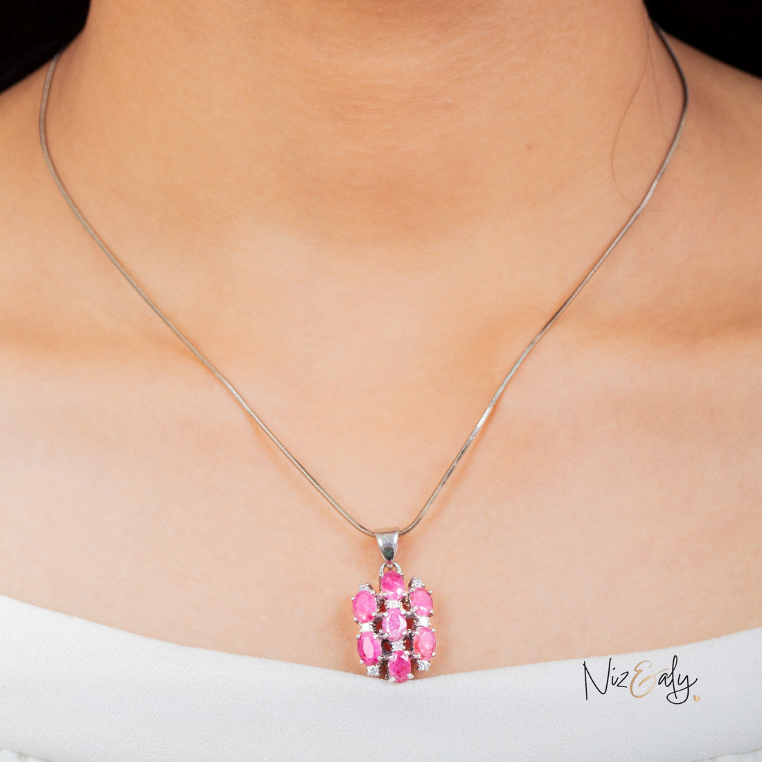 Niz & Aly cluster pendant featuring seven high-quality red rubies set in silver, worn on a delicate chain.