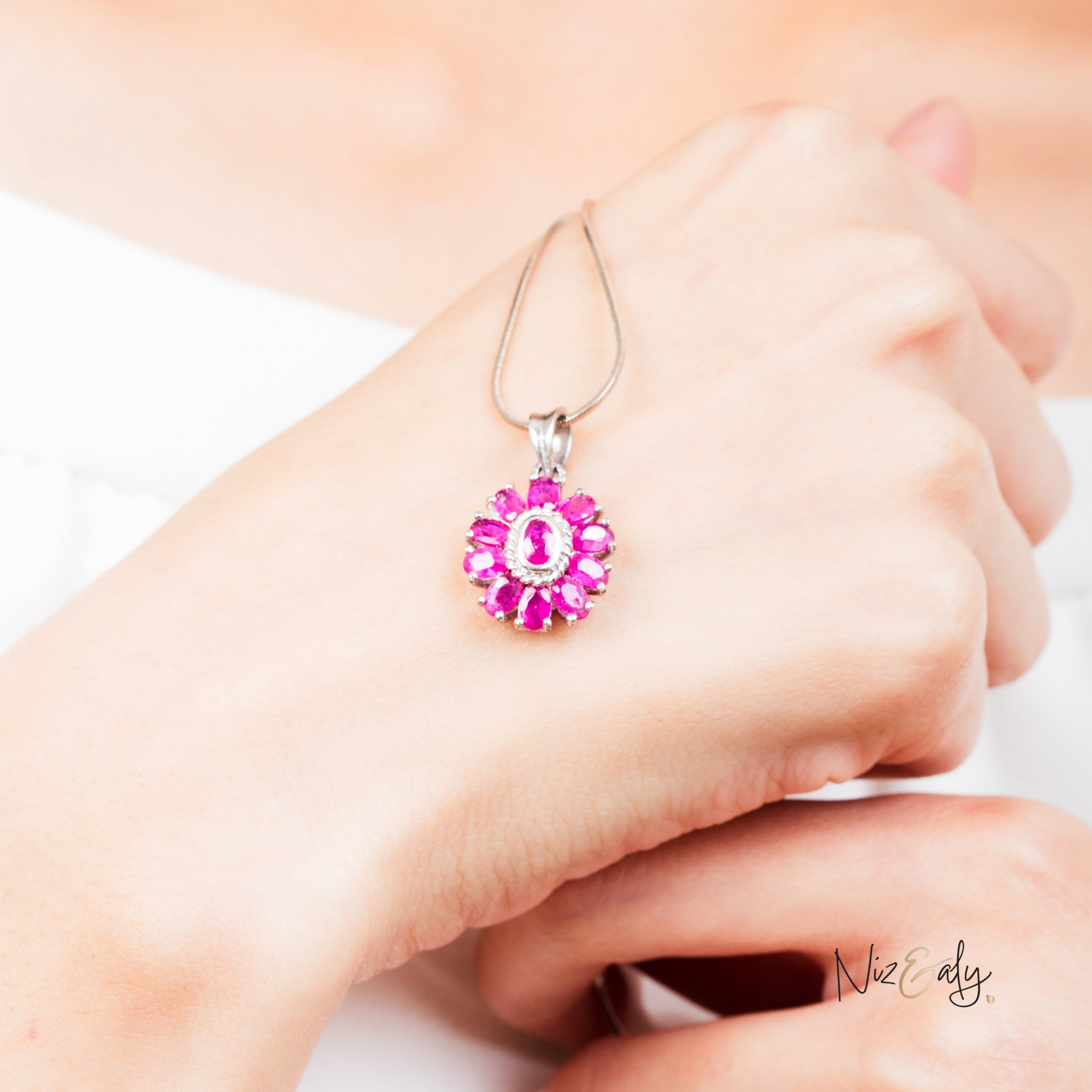 Niz & Aly Nothing But Rubies necklace featuring 33 vibrant red rubies in a floral silver setting worn on a hand