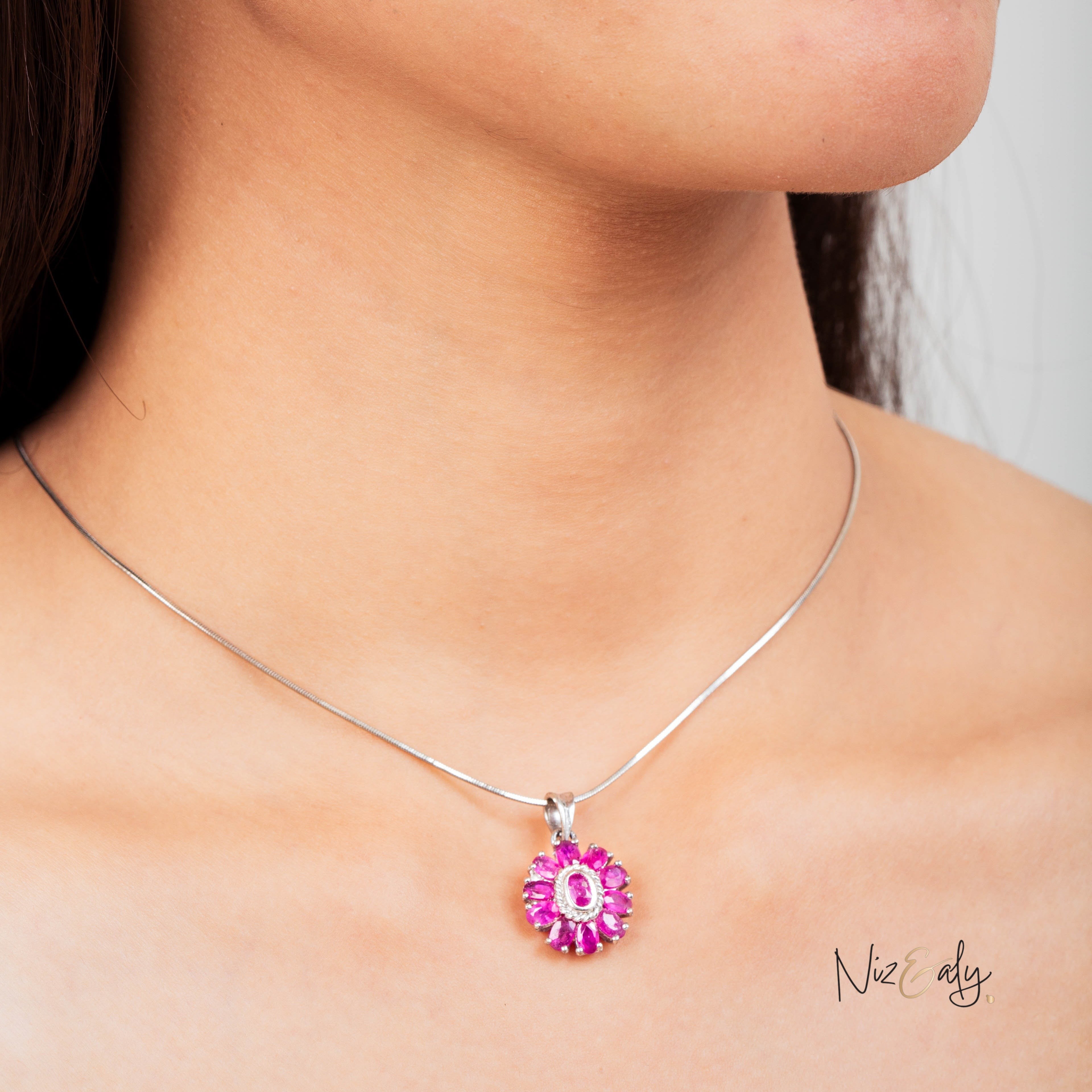 Niz & Aly Nothing But Rubies necklace featuring 33 vibrant red rubies in a floral cluster pendant on a silver chain