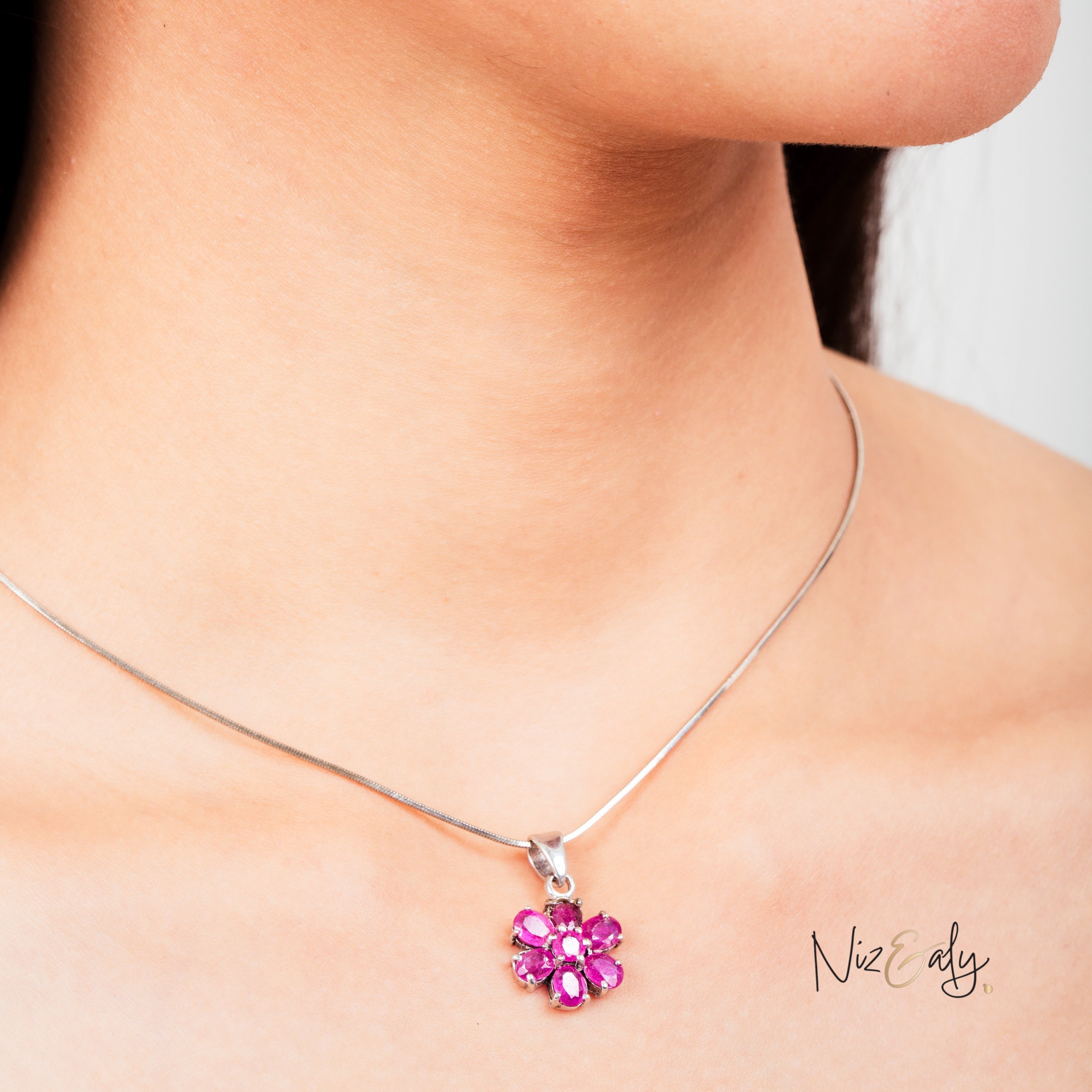 Niz & Aly ruby flower pendant featuring seven vibrant red rubies set in a floral design on a silver chain