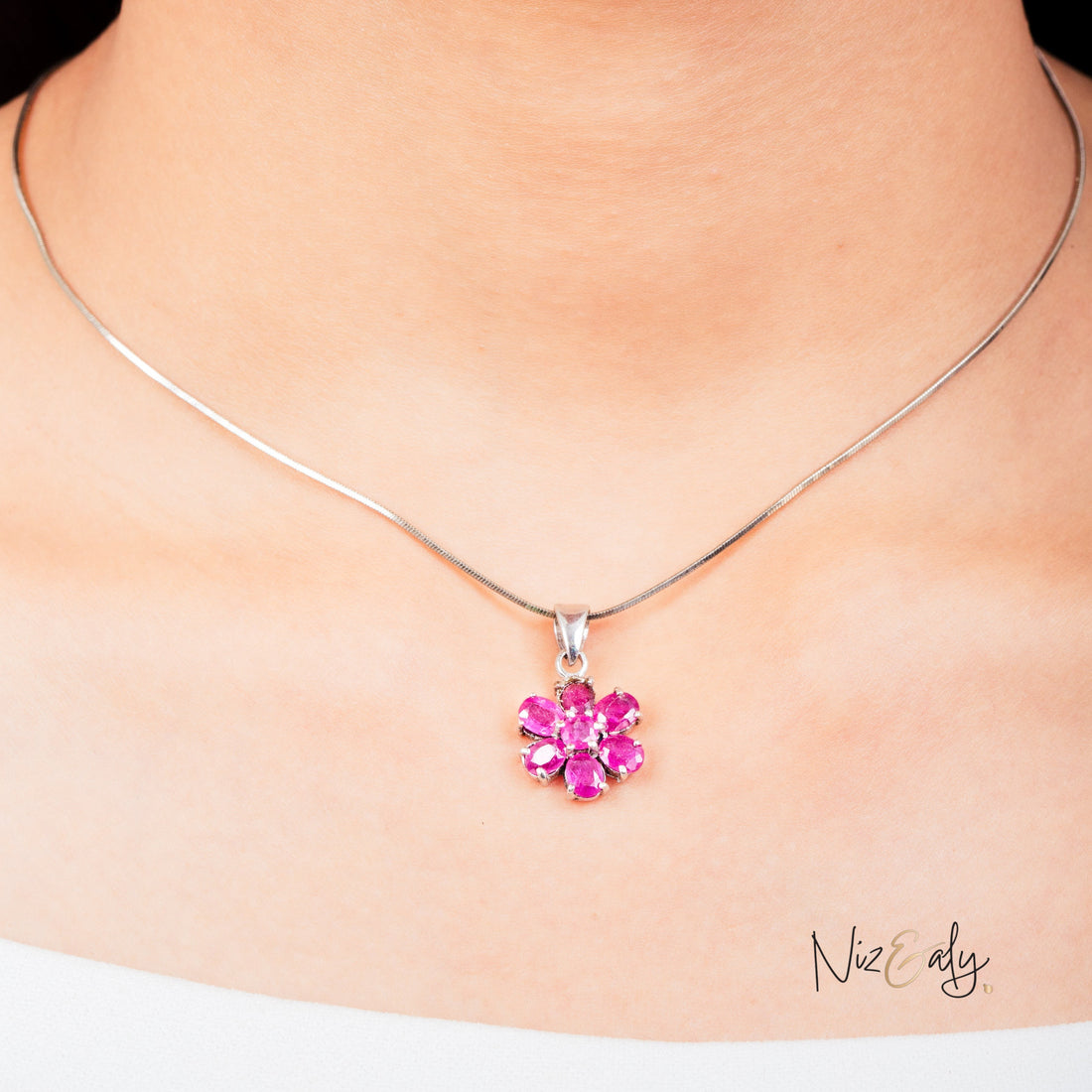 Niz & Aly ruby flower pendant featuring seven vibrant red rubies set in a delicate floral design on a silver chain