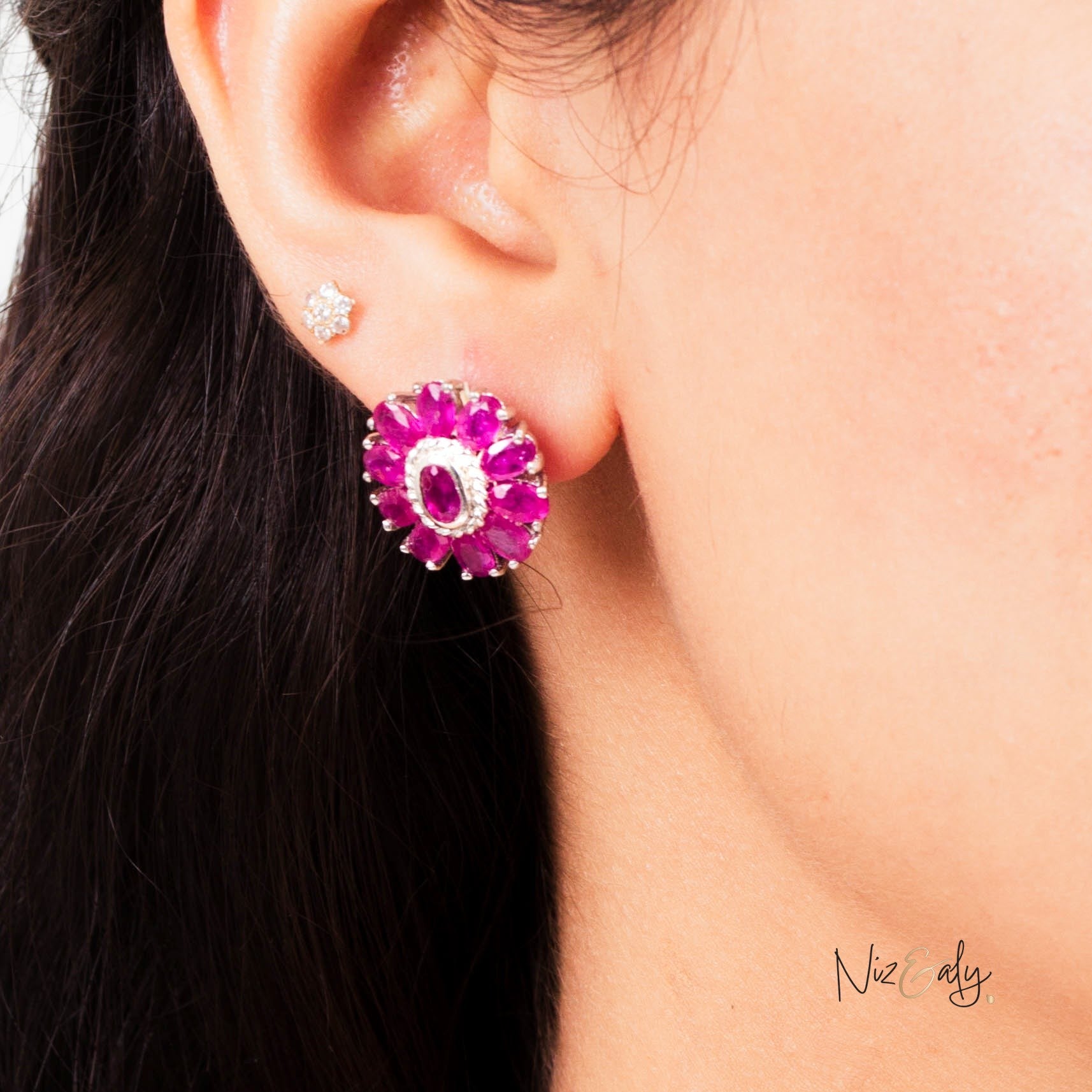 Niz & Aly ruby flower stud earring featuring a cluster of vibrant red rubies worn on a woman's earlobe