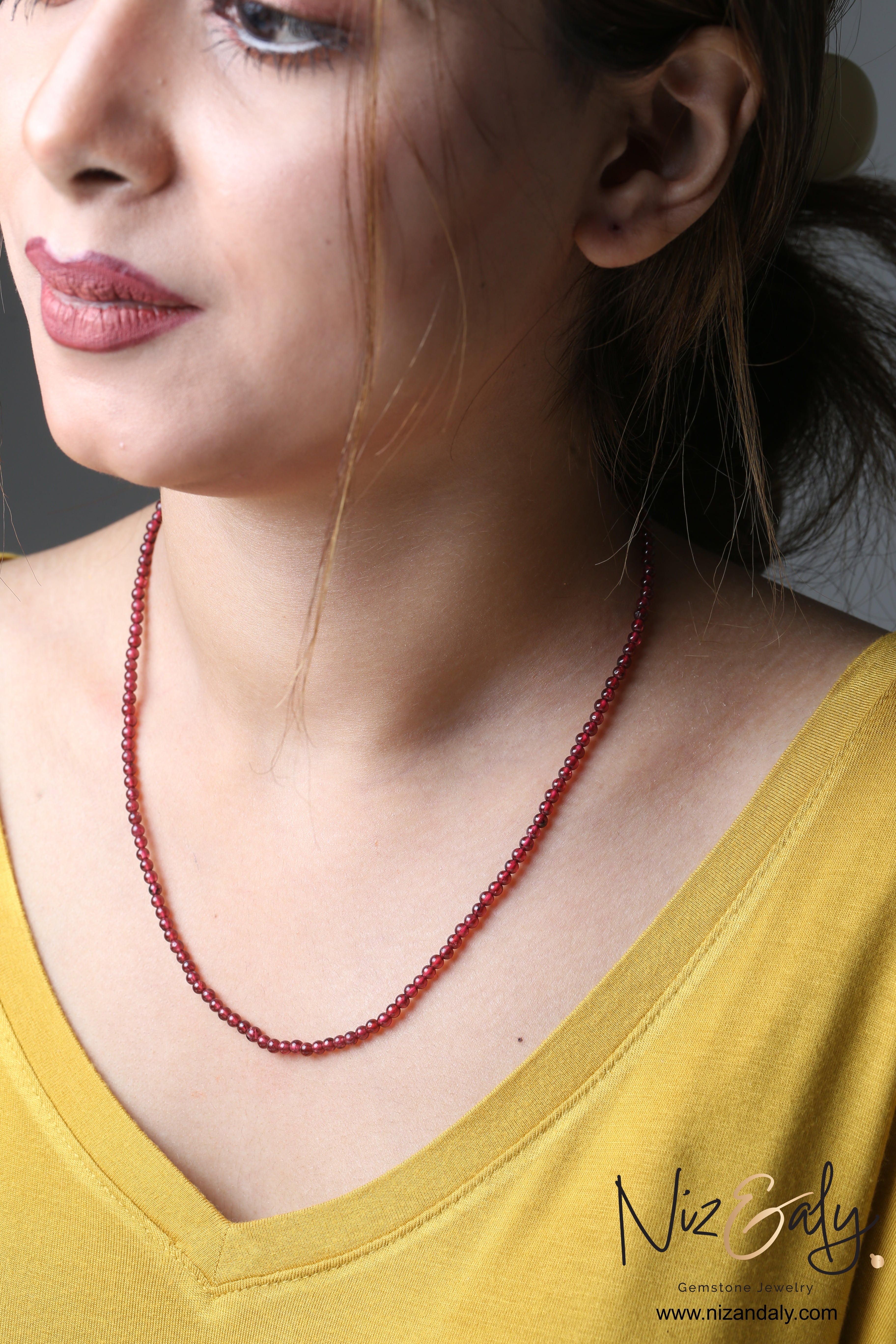 Niz & Aly Ruby-Glow Garnet Necklace featuring delicate 3mm deep red natural gemstone beads worn by a woman