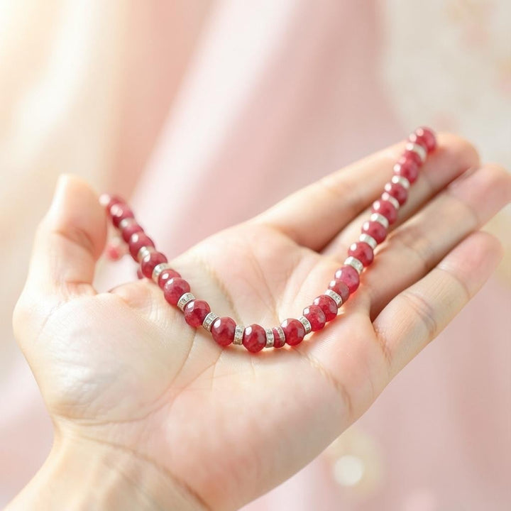 Niz & Aly ruby red faceted jade beaded necklace with silver spacers held in a hand