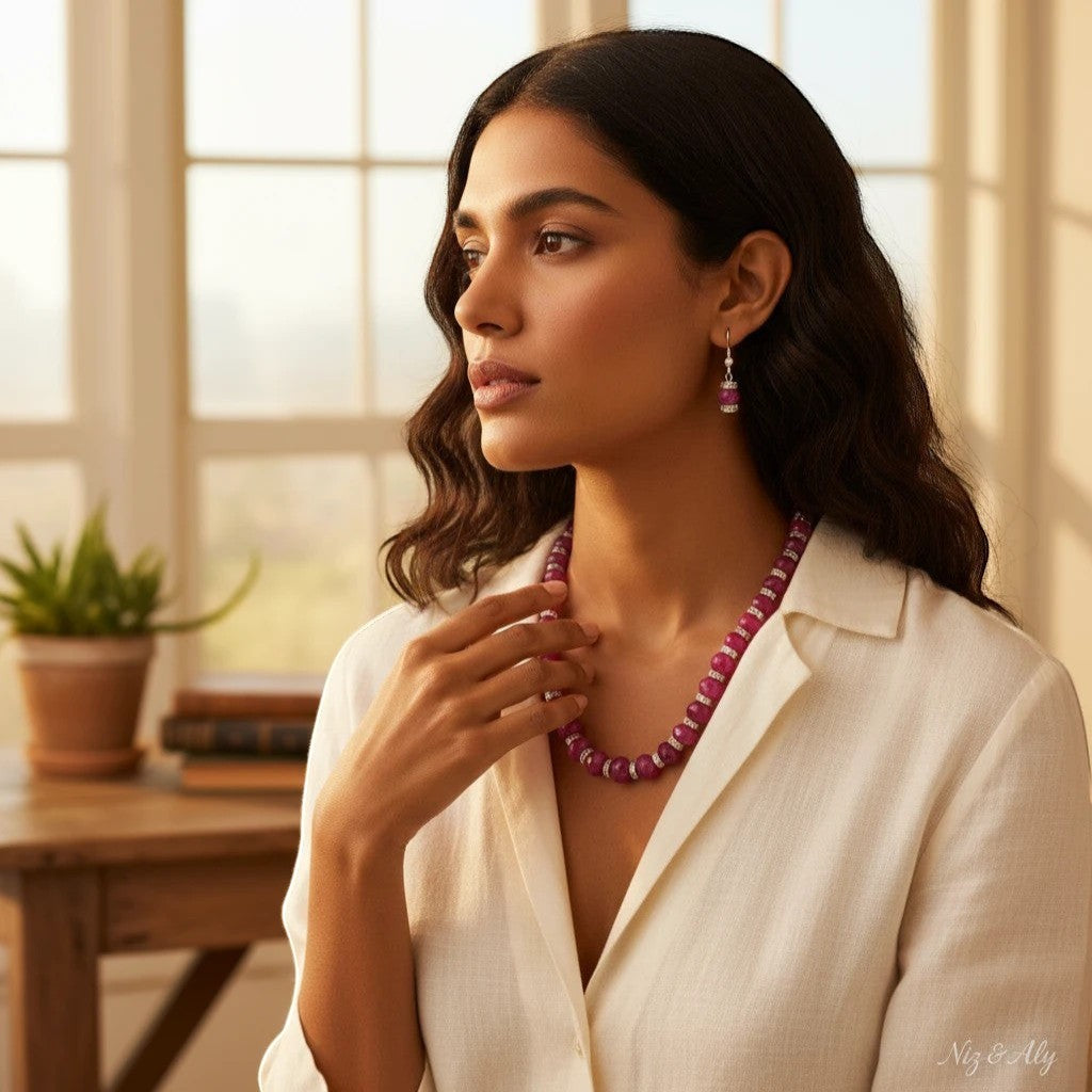 Niz & Aly ruby red faceted jade graduated necklace and drop earrings worn by a woman in a white linen shirt.