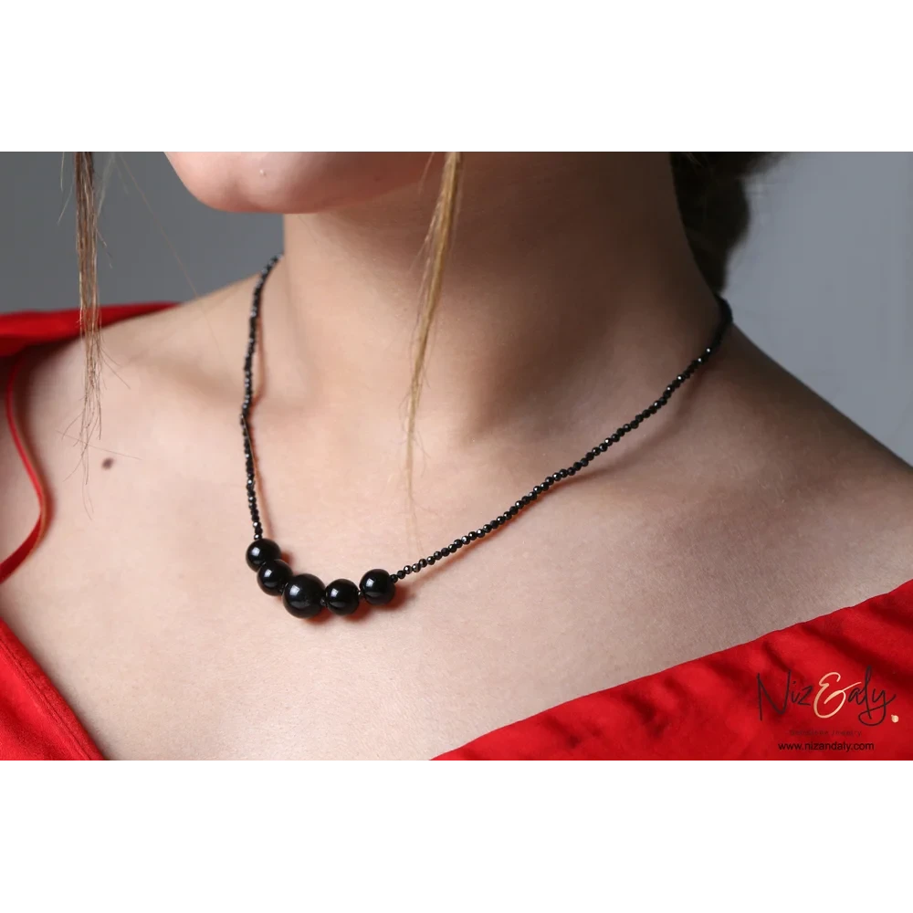 Niz & Aly dainty necklace featuring natural Shungite stones and faceted Onyx beads on a model wearing a red top.