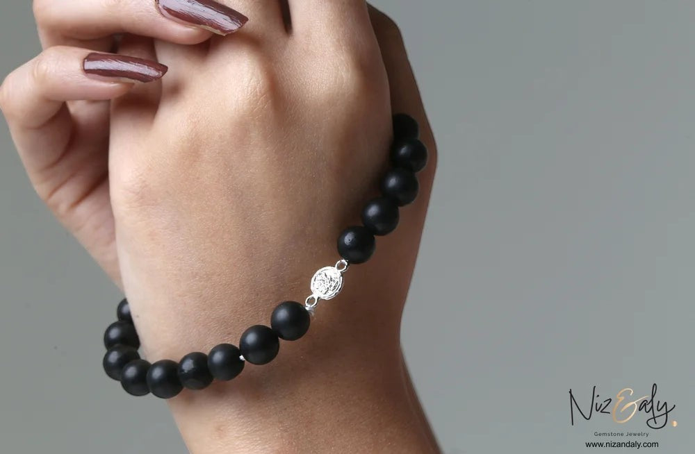 Niz & Aly genuine matte black Shungite stretch bracelet with a polished 925 sterling silver accent bead on a wrist.