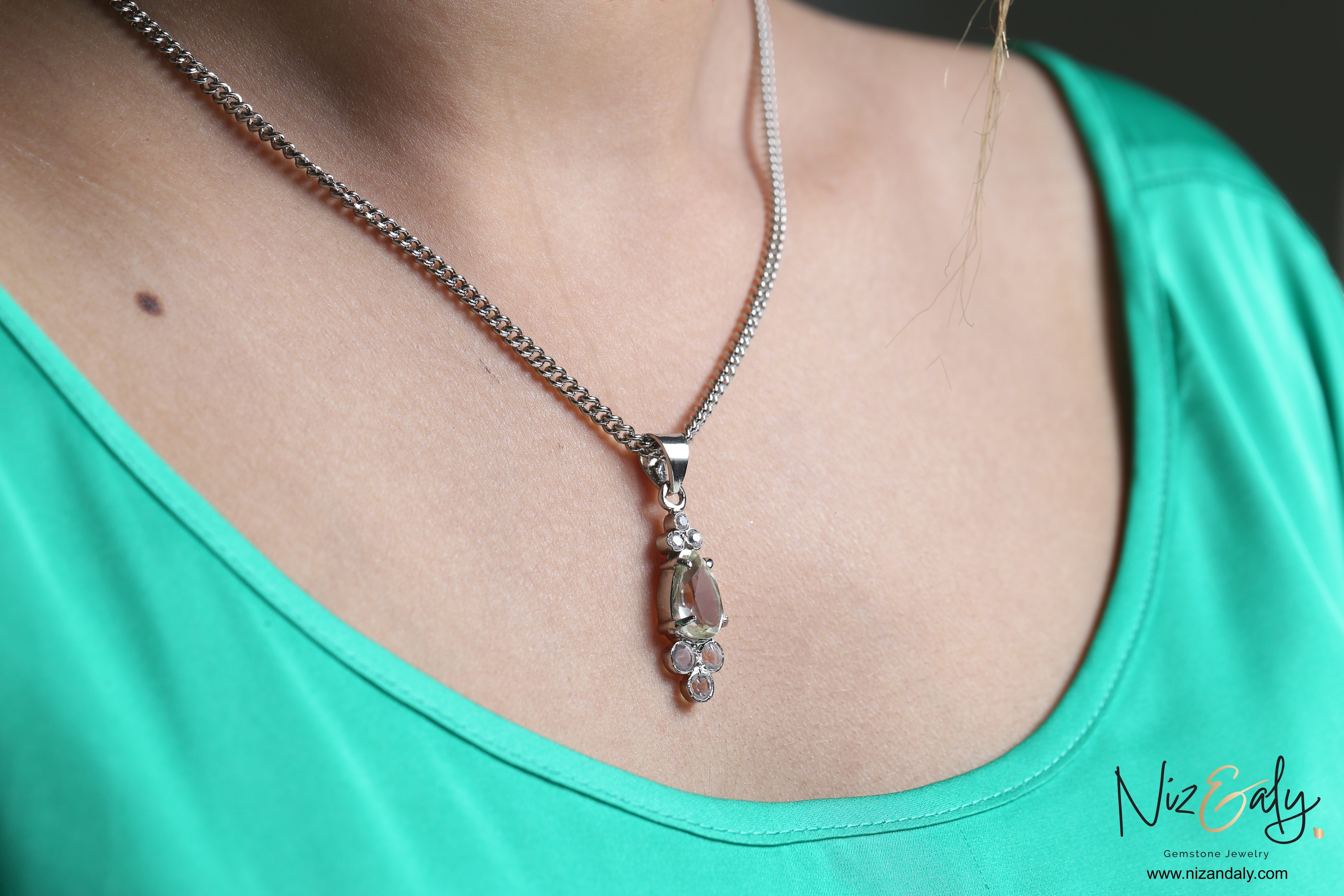 Niz & Aly Silver Moonlight teardrop clear quartz pendant necklace on a woman wearing a green top