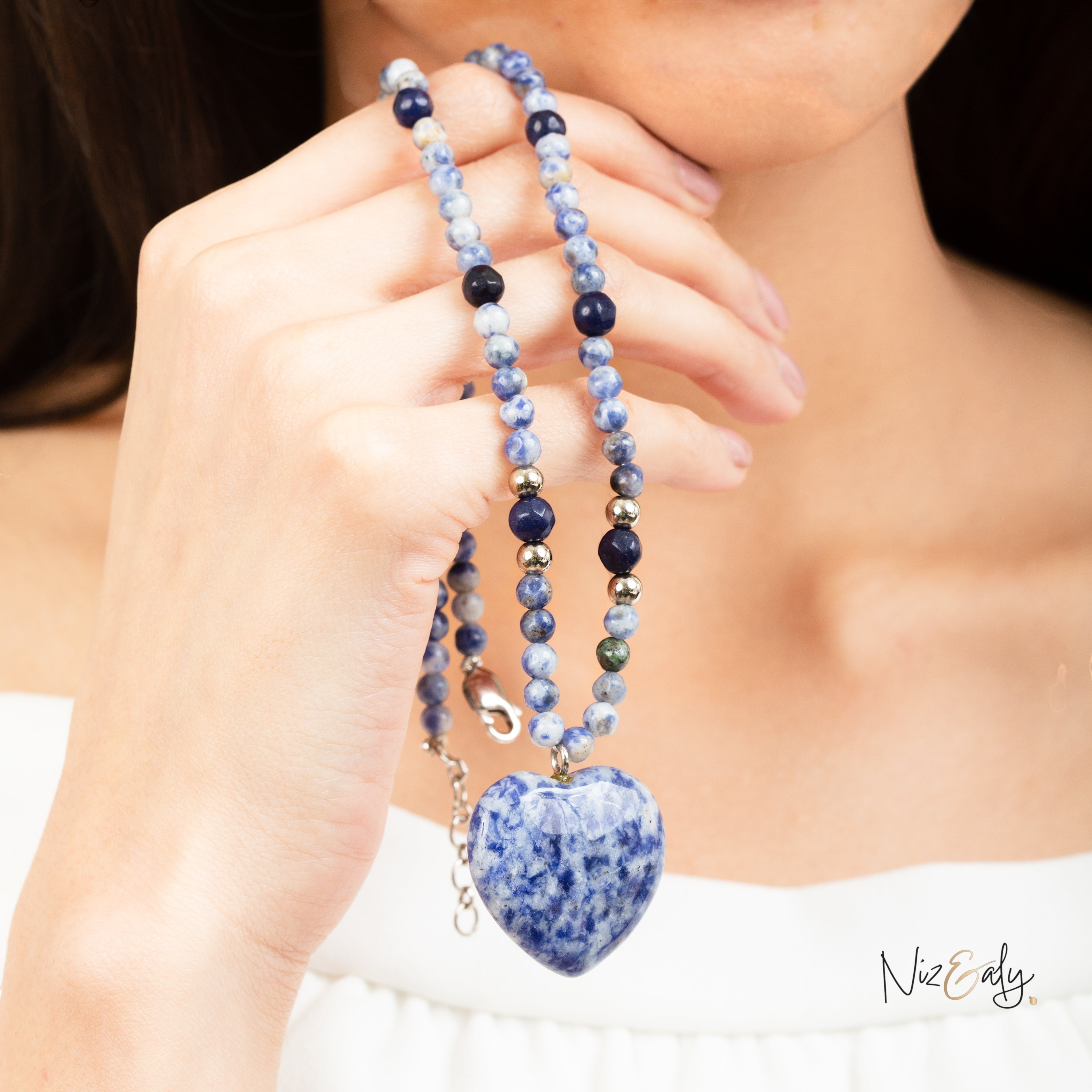 Niz & Aly sodalite heart pendant necklace with beaded Canadian blue stone strand worn by a woman in a white top.