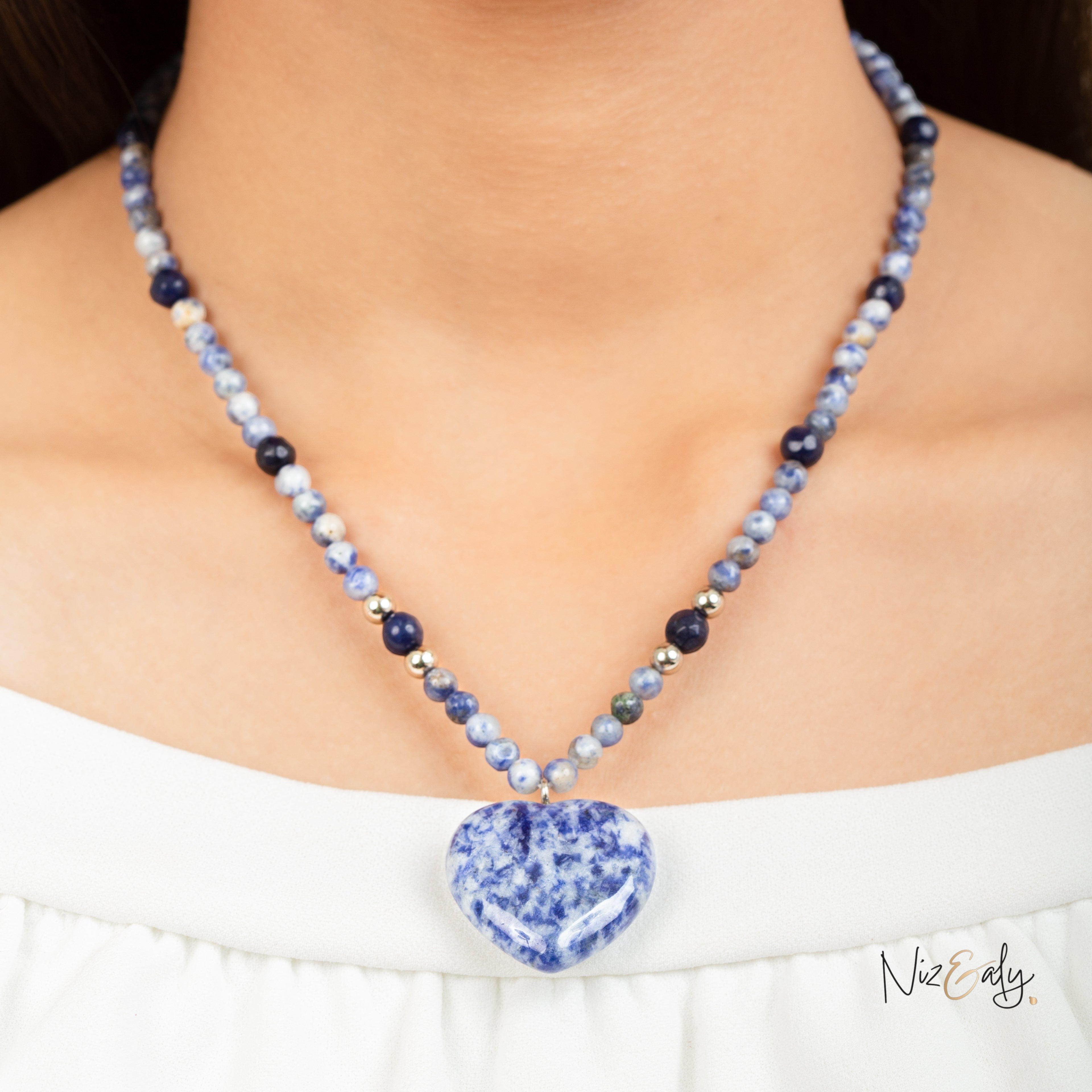 Niz & Aly sodalite heart pendant necklace with natural blue stone beads worn on a model in a white top.
