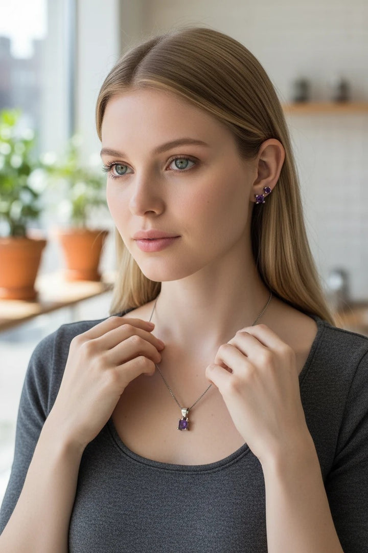Niz & Aly dainty square amethyst necklace and stud earring set worn by a blonde woman in a grey top