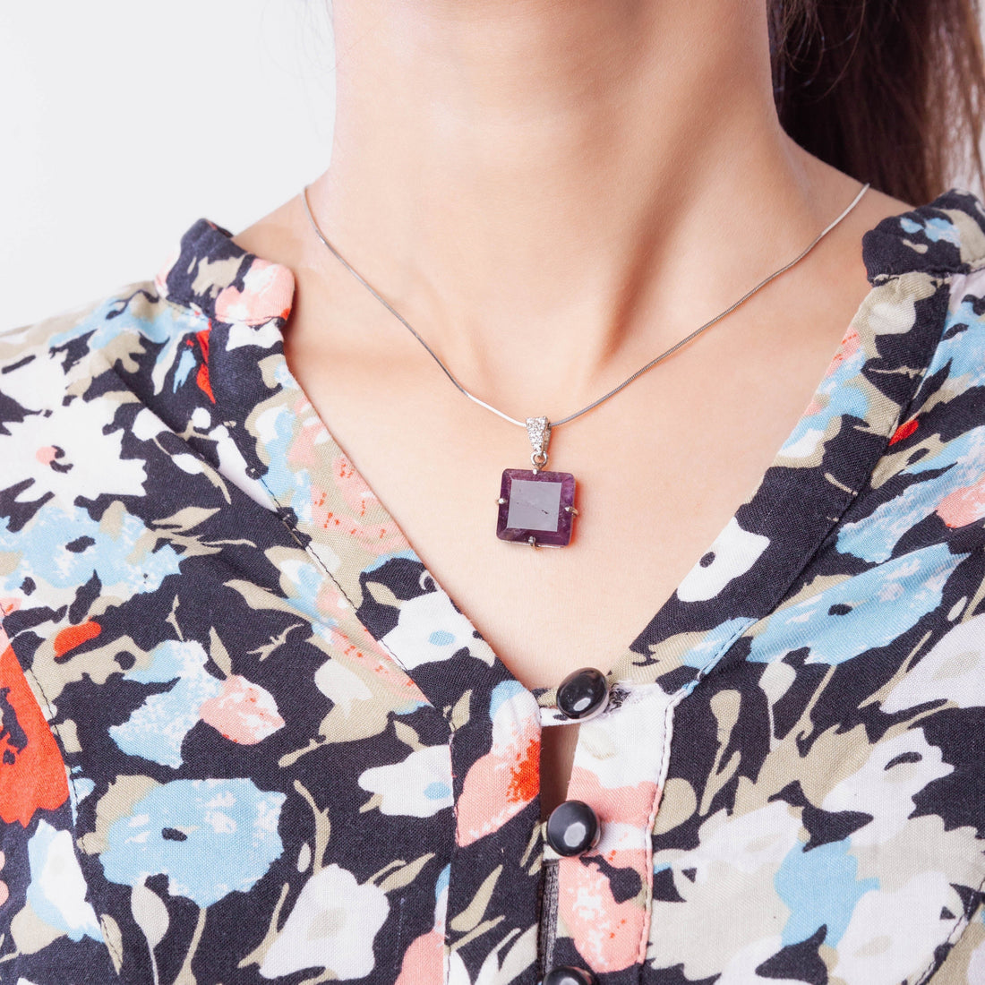 Niz & Aly square amethyst locket pendant on a silver chain worn by a woman in a floral blouse
