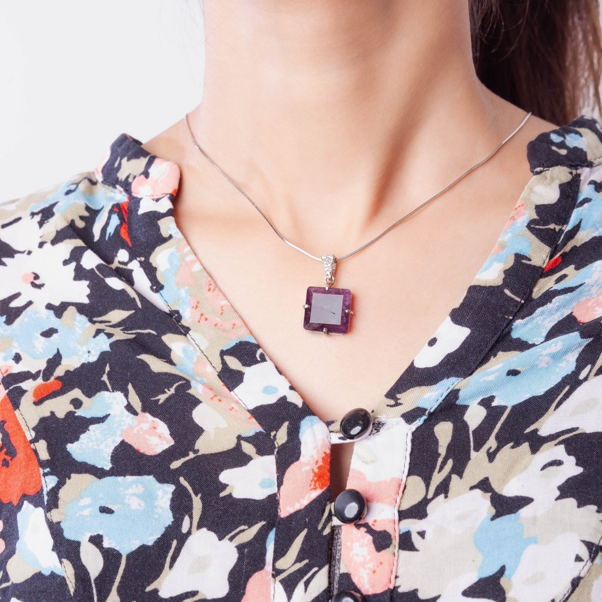 Niz & Aly square amethyst locket pendant on a silver chain worn by a woman in a floral blouse
