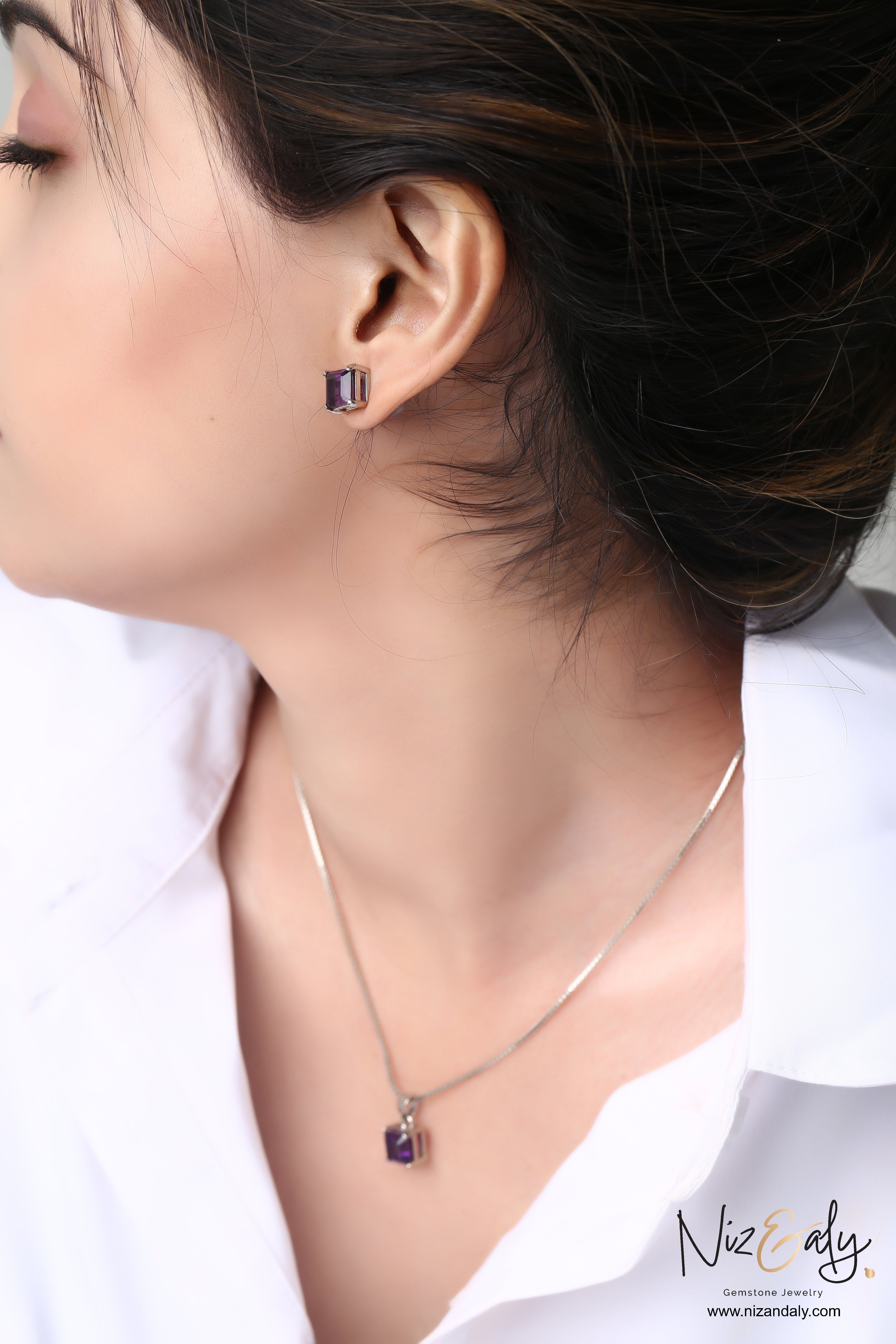 Niz & Aly square-cut amethyst pendant and matching stud earrings worn by a woman in a white shirt