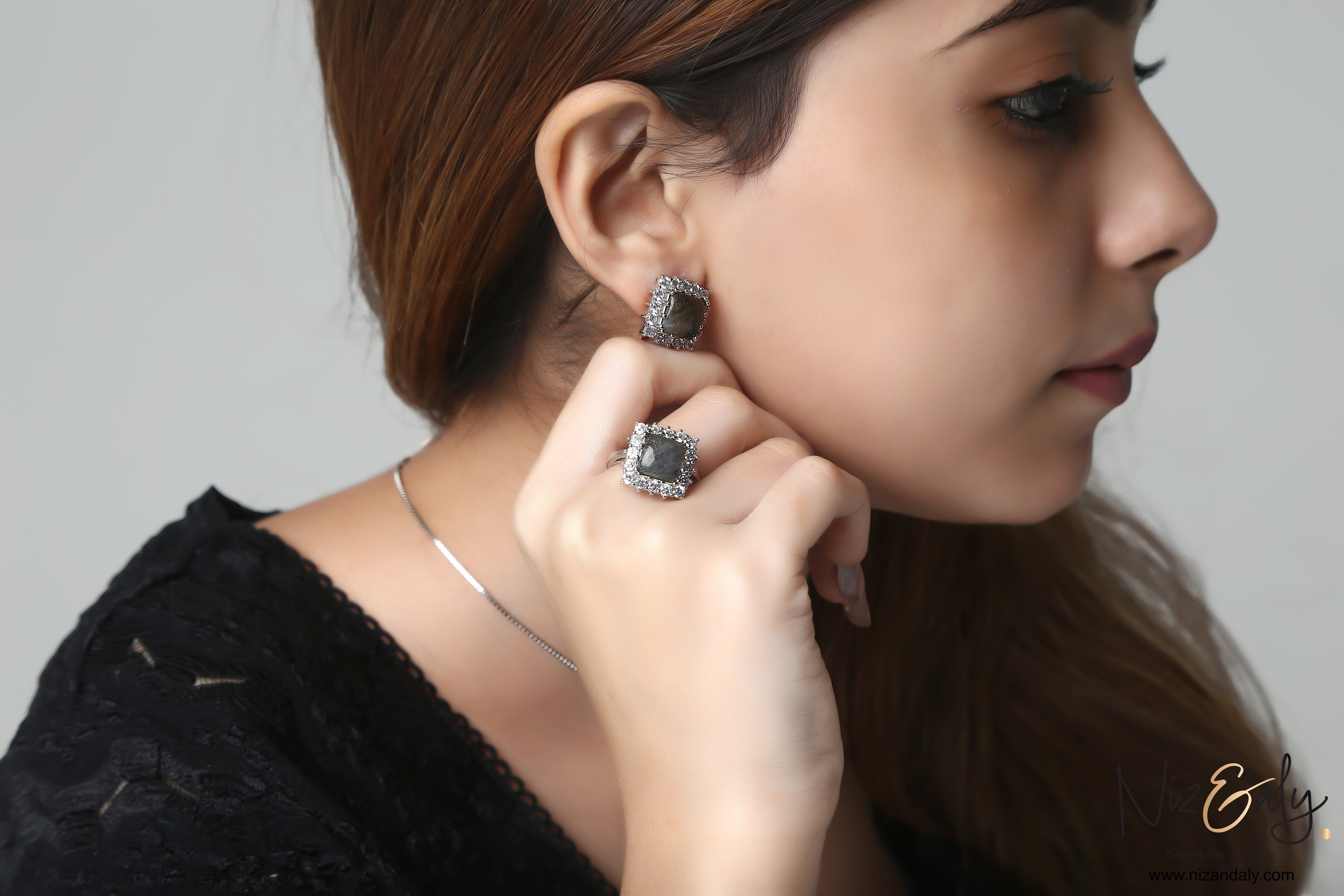 Niz & Aly square labradorite pendant and earring set with blue fire flash worn by a woman against a white background