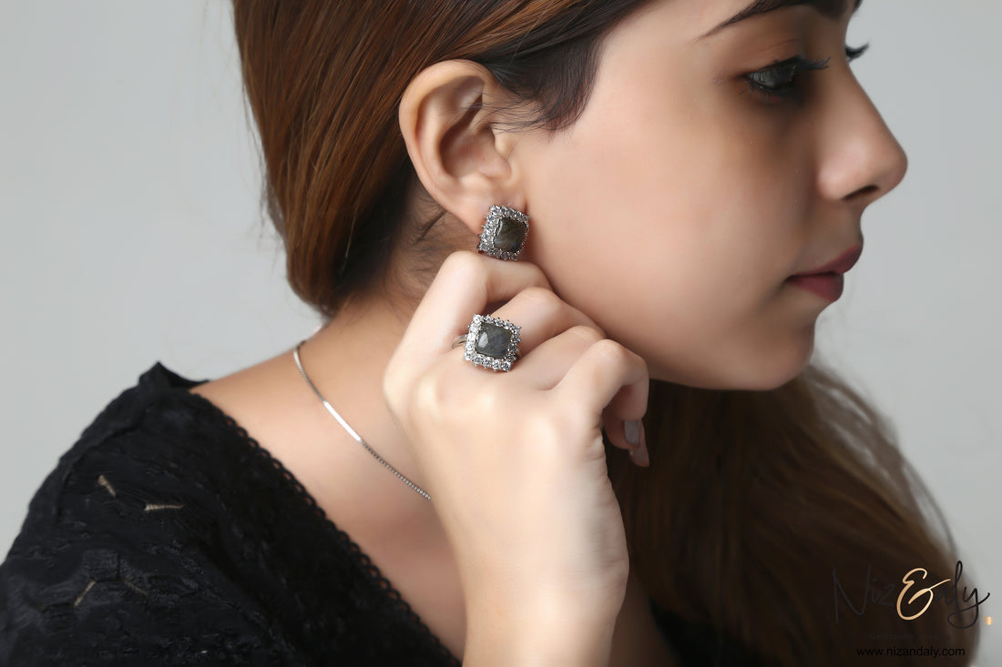 Niz & Aly square labradorite pendant and earring set with blue fire flash worn by a woman against a white background