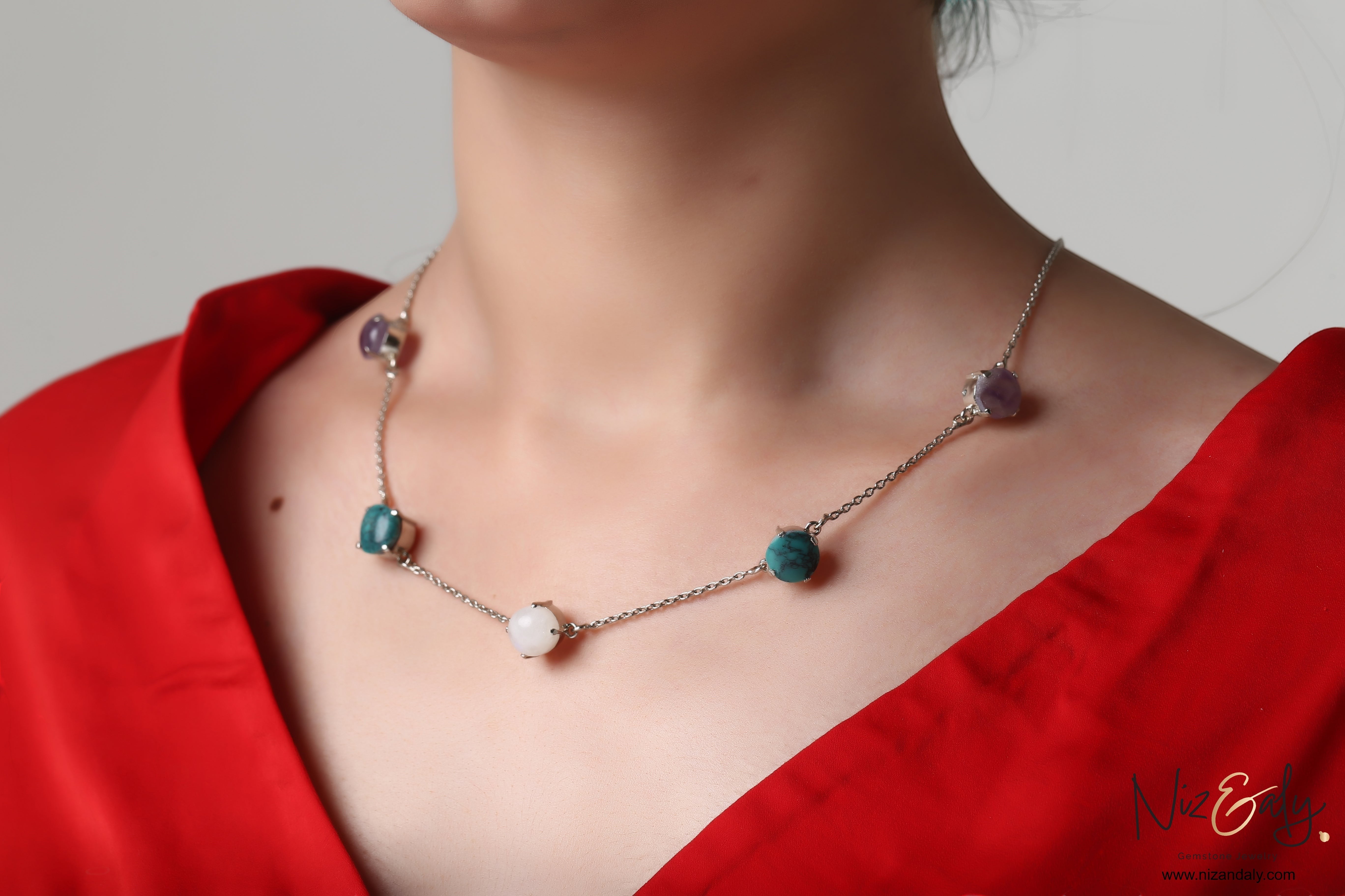 Niz & Aly sterling silver necklace featuring amethyst, turquoise, and milky quartz stones on a model in a red top.