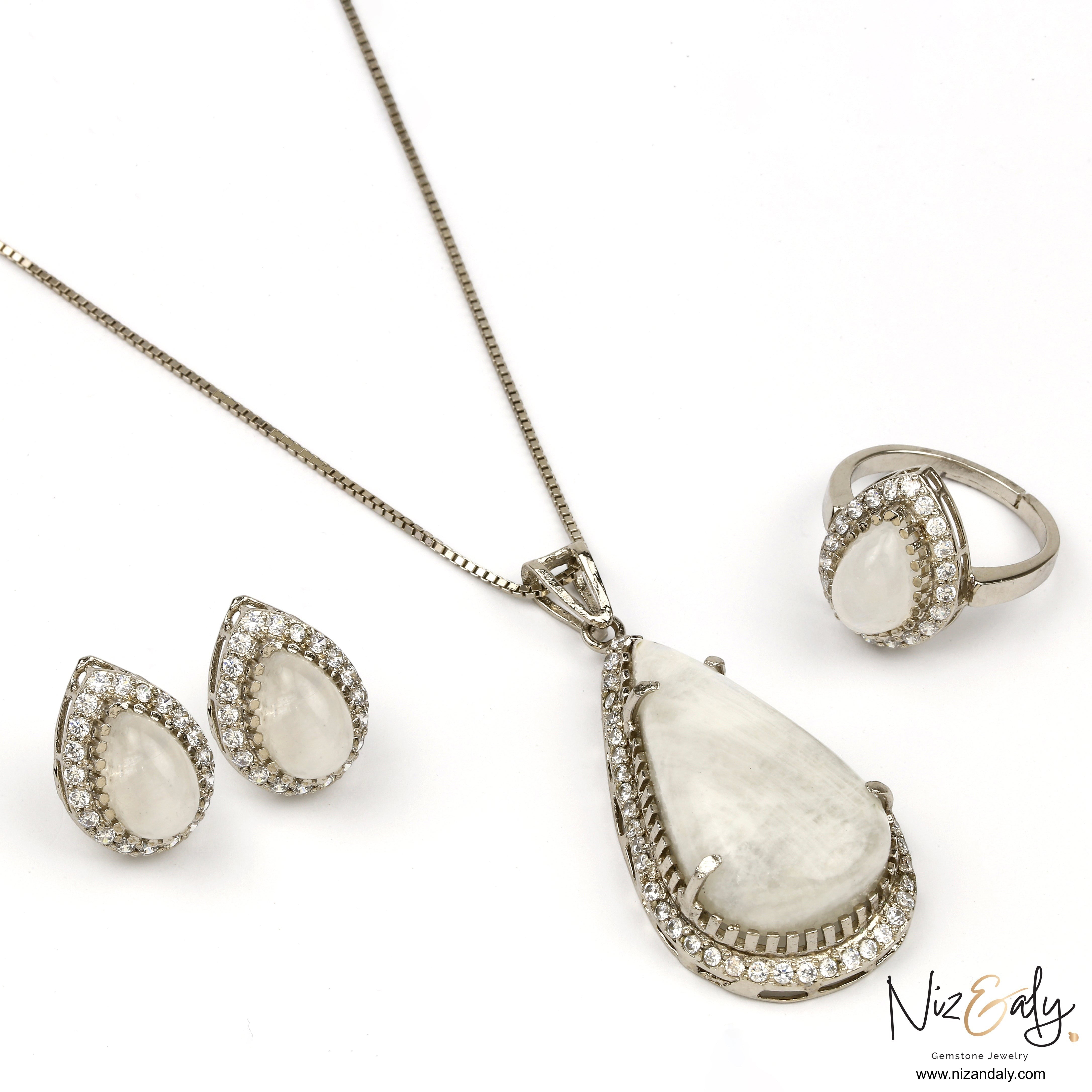 Niz & Aly teardrop moonstone jewelry set with blue flash, featuring a pendant, earrings, and ring in silver setting.