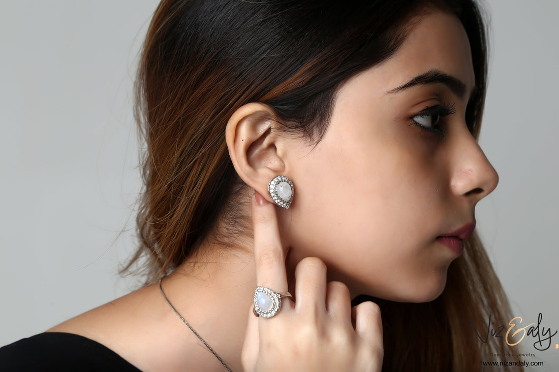 Niz & Aly teardrop moonstone earrings and ring set with blue flash, worn by a woman in profile.