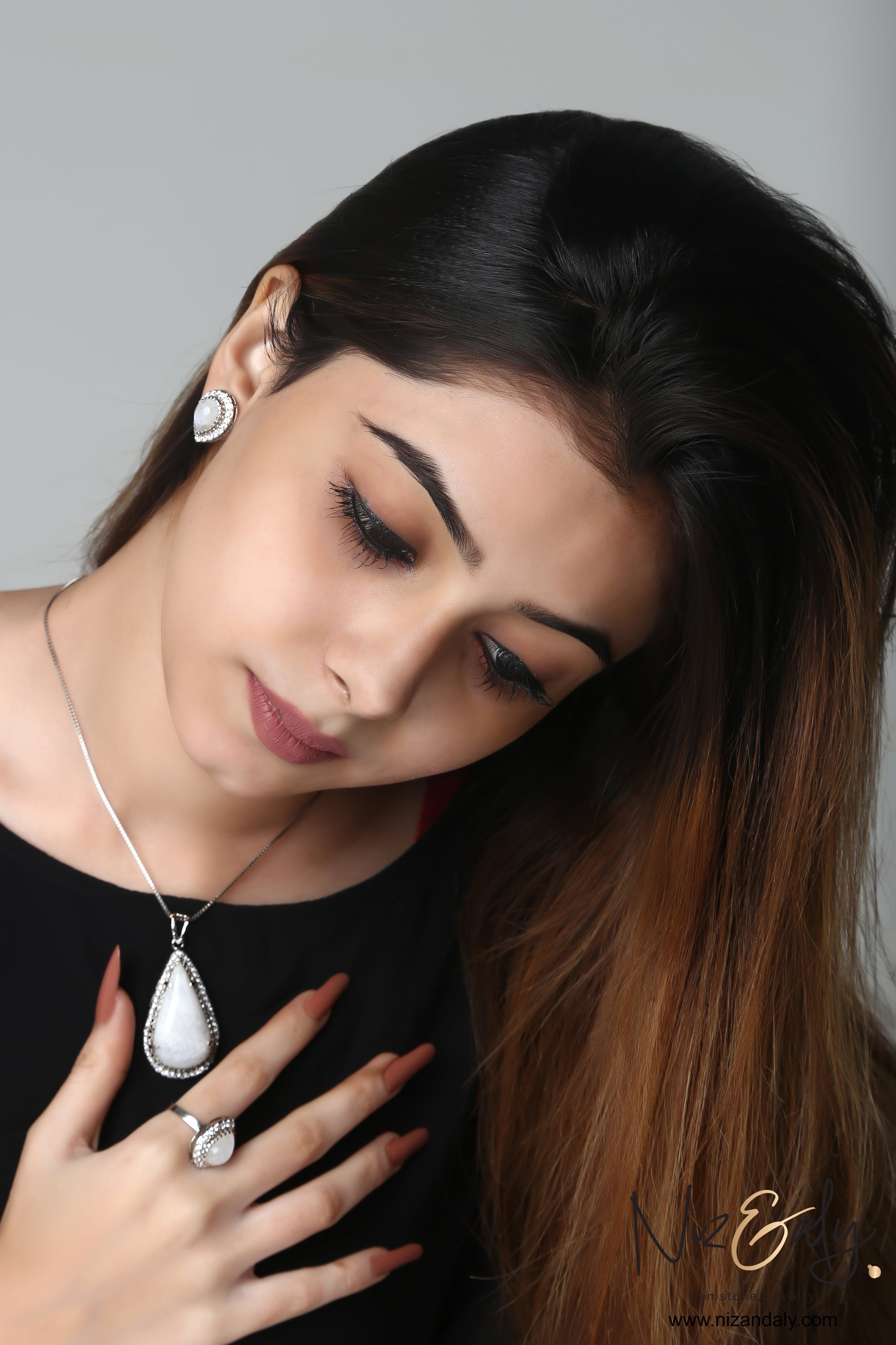 Niz & Aly teardrop moonstone pendant set with blue flash worn by a woman with a matching ring and stud earrings