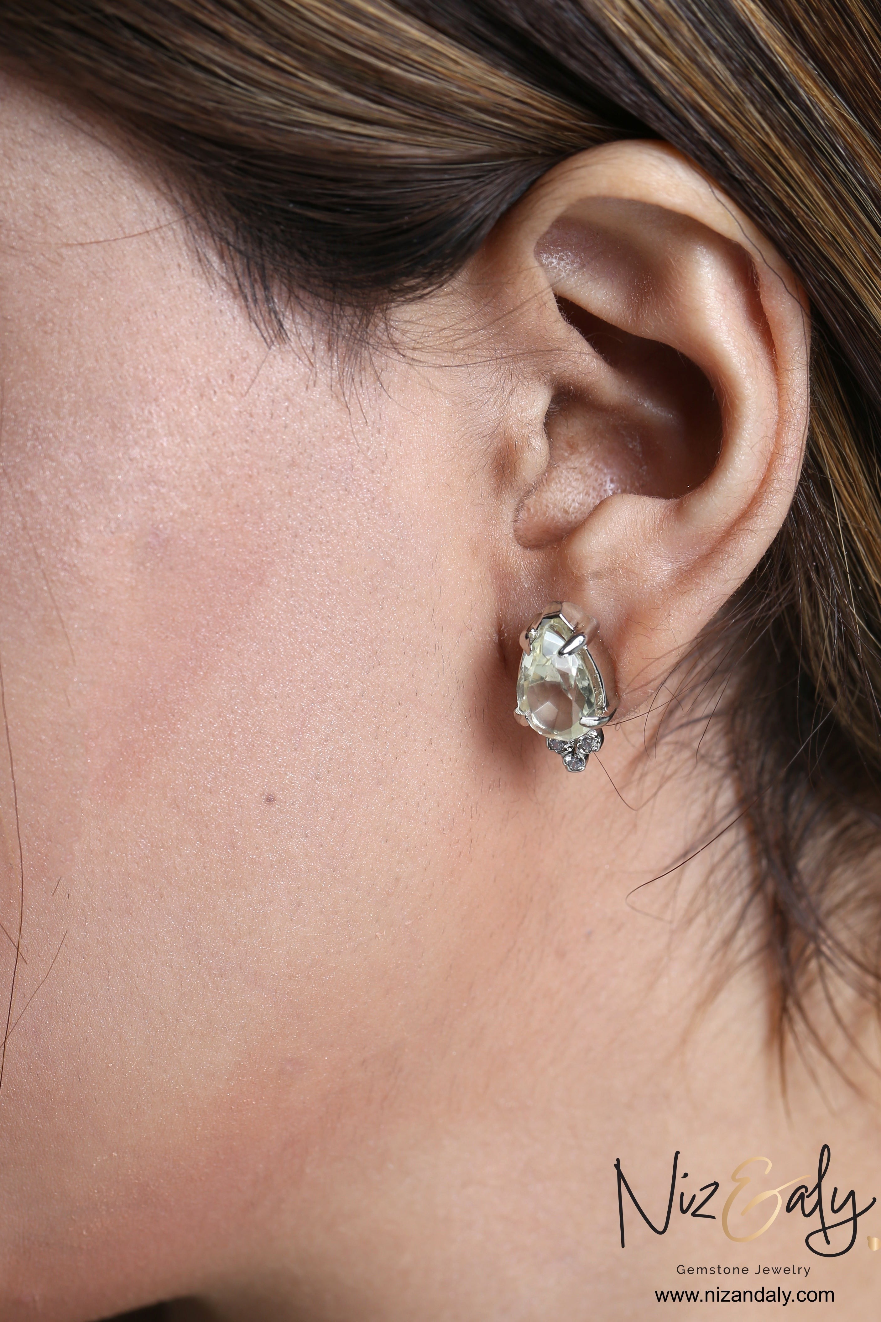 Niz & Aly teardrop clear quartz stud earring in silver setting worn on a woman's earlobe
