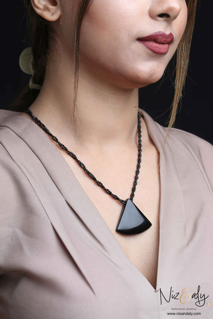 Niz & Aly Agate Eclipse necklace featuring a black triangular agate pendant on a twisted black onyx bead chain.