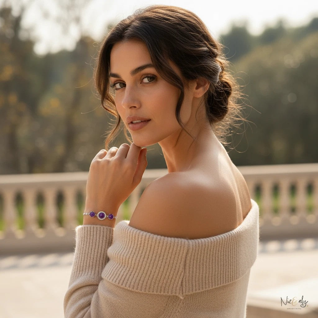 A woman wearing a Niz & Aly triple amethyst bracelet with faceted purple crystal beads on a soft beige off-shoulder top