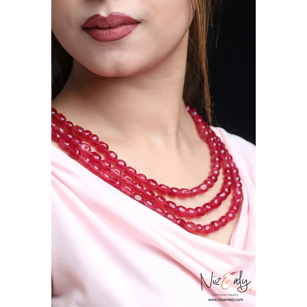 Niz & Aly triple strand cherry quartz beaded necklace worn by a model, featuring polished translucent red gemstones.