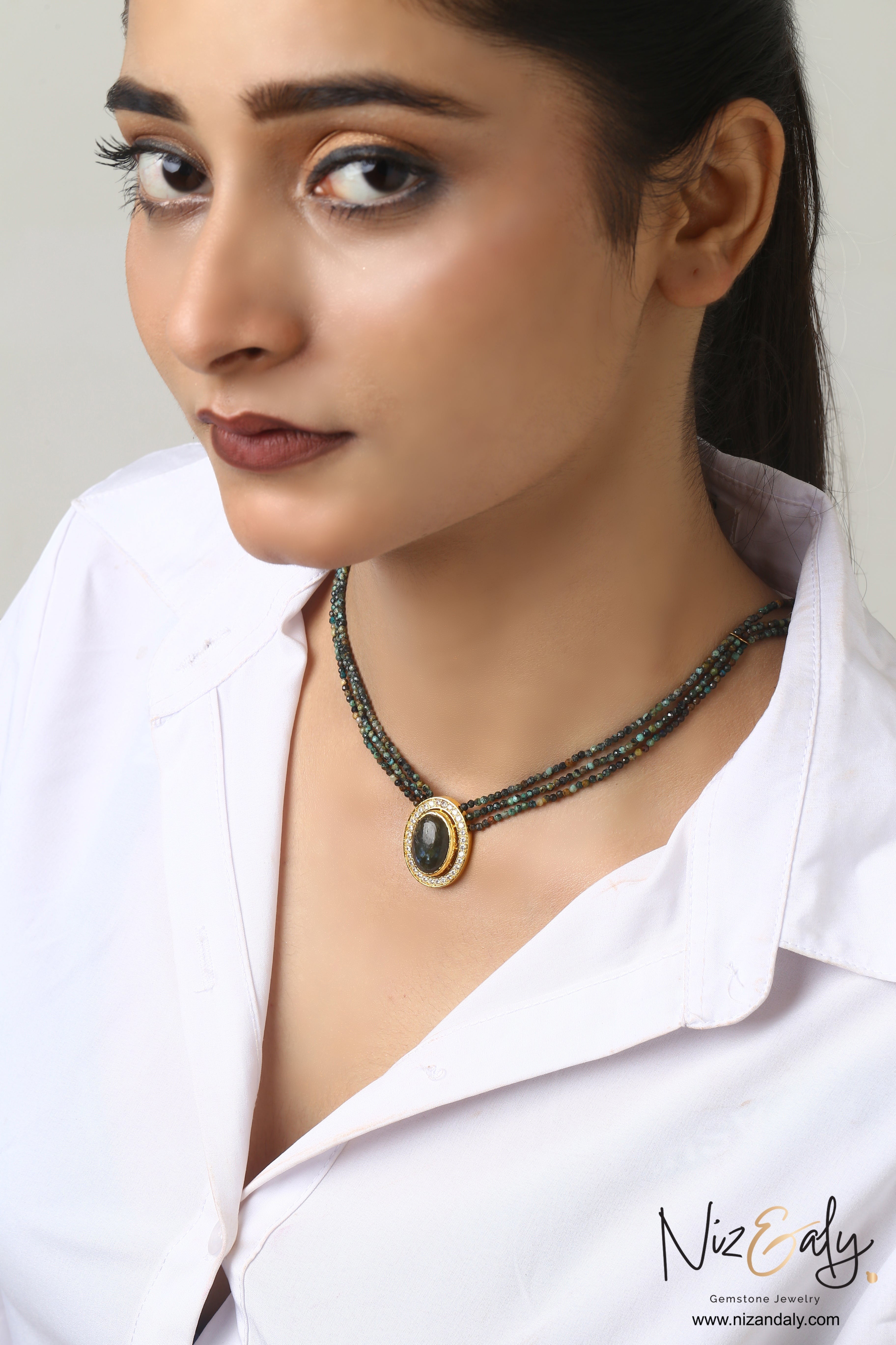 Niz & Aly triple strand beaded gemstone necklace with an oval center stone and crystal halo on a model