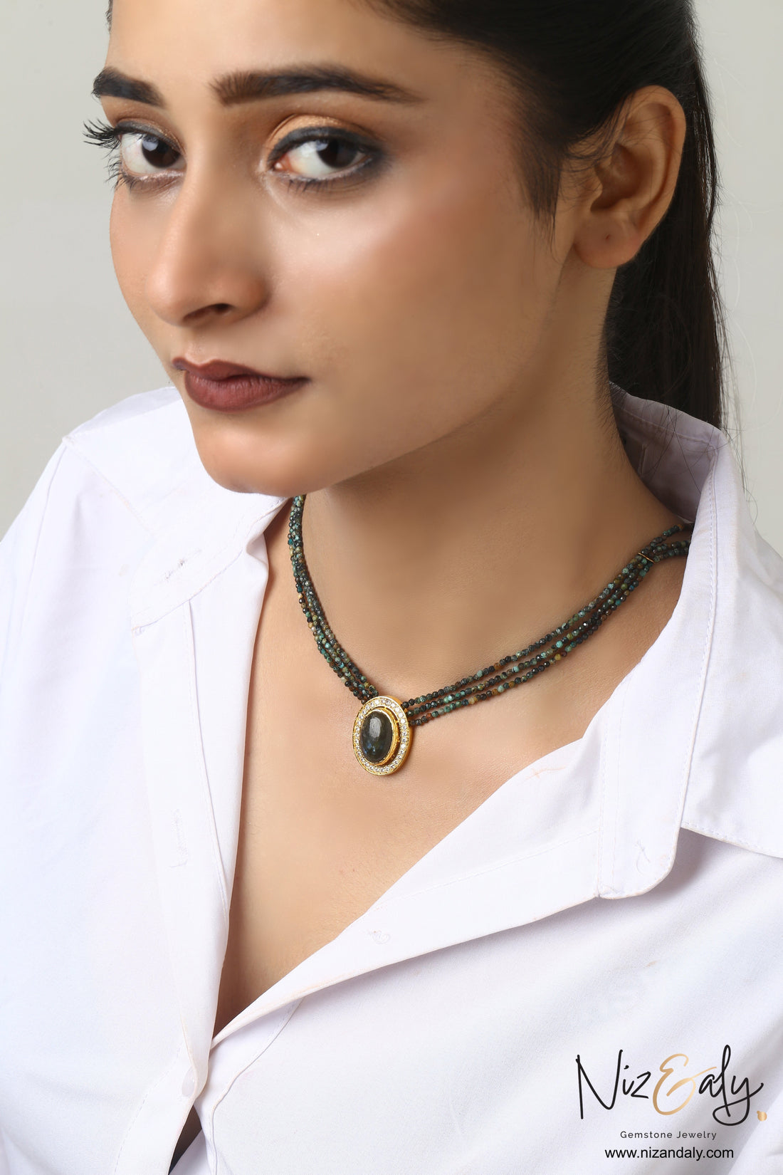 Niz & Aly triple strand beaded gemstone necklace with an oval center stone and crystal halo on a model