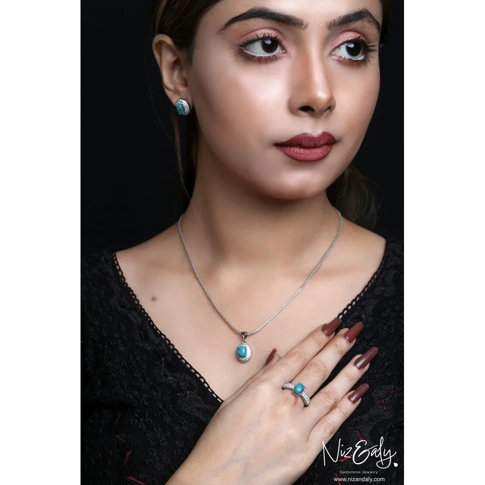 Model wearing Niz & Aly oval turquoise gemstone necklace, stud earrings, and ring with cubic zirconia halo in silver