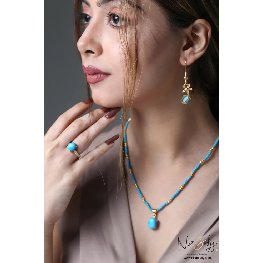 Niz & Aly turquoise gemstone necklace, drop earrings, and ring set with gold-tone accents worn by a model