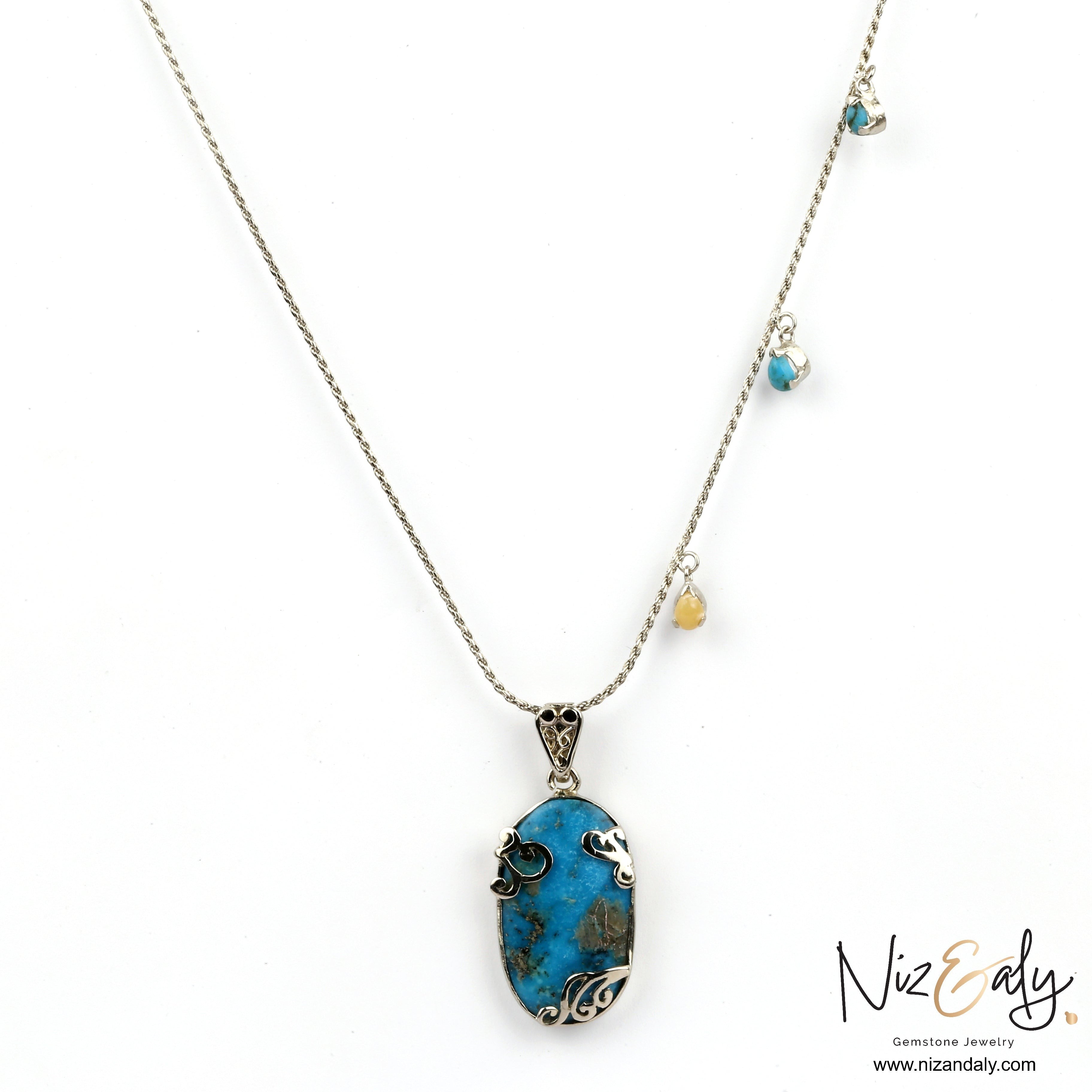 Niz & Aly oval turquoise pendant necklace with silver filigree detail and small gemstone charms on a delicate chain.