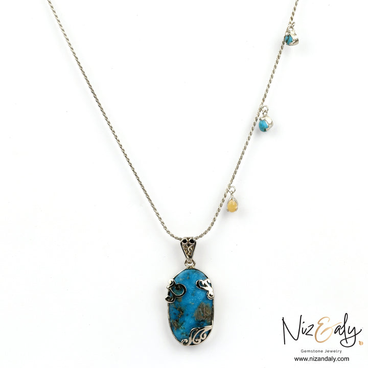 Niz & Aly oval turquoise pendant necklace with silver filigree detail and small gemstone charms on a delicate chain.