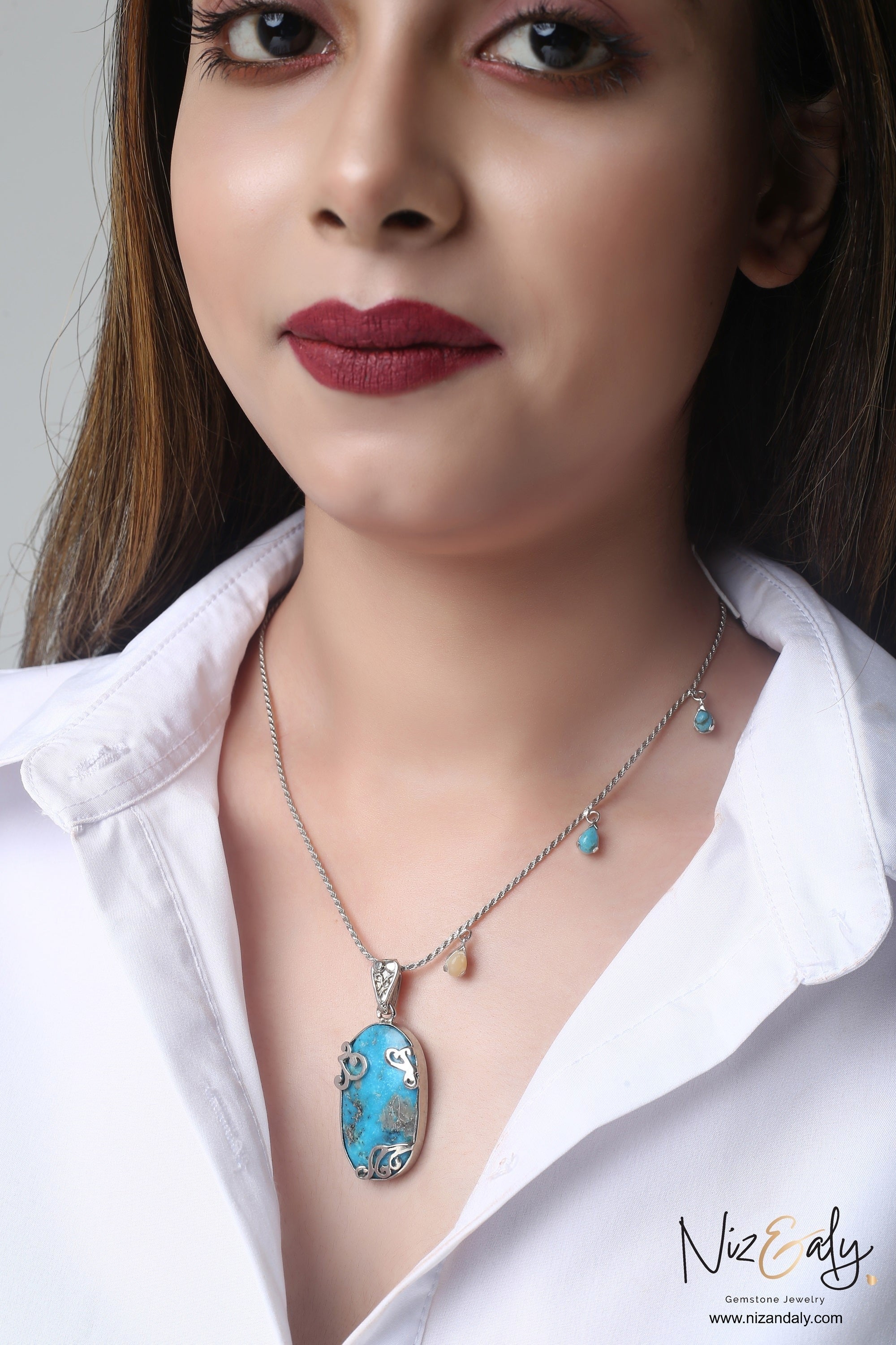 Niz & Aly turquoise pendant necklace featuring an oval gemstone on a delicate silver chain worn by a woman